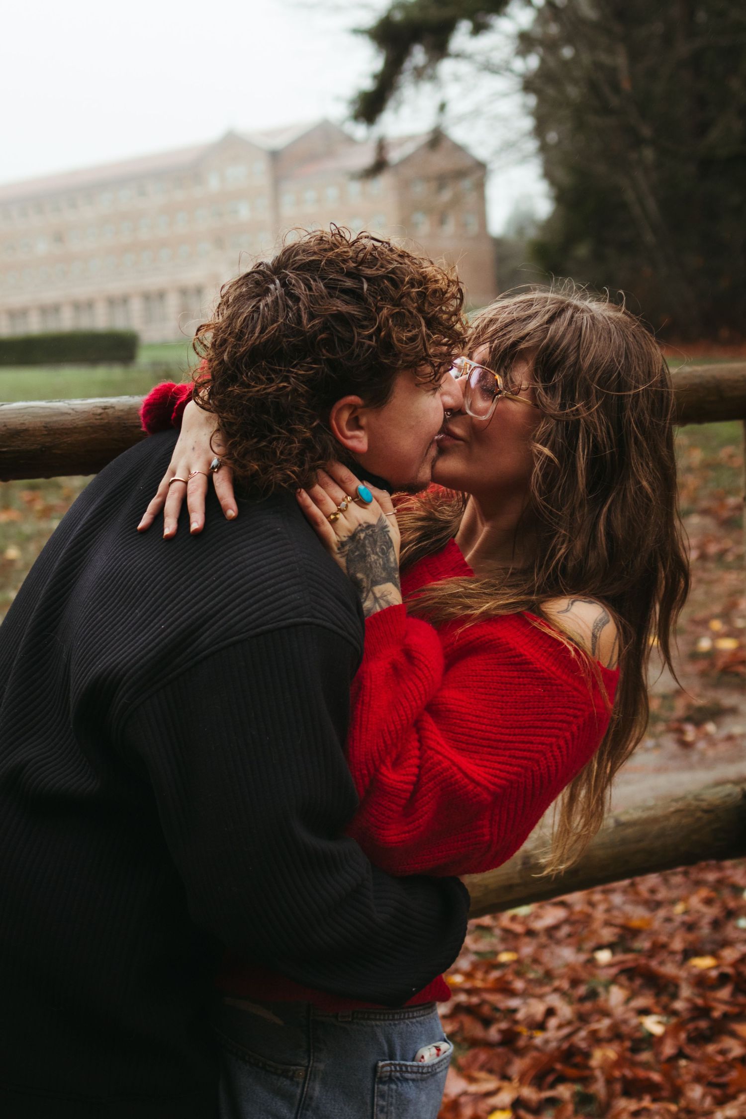 A romantic autumn scene with fallen leaves as a couple embraces outdoors.