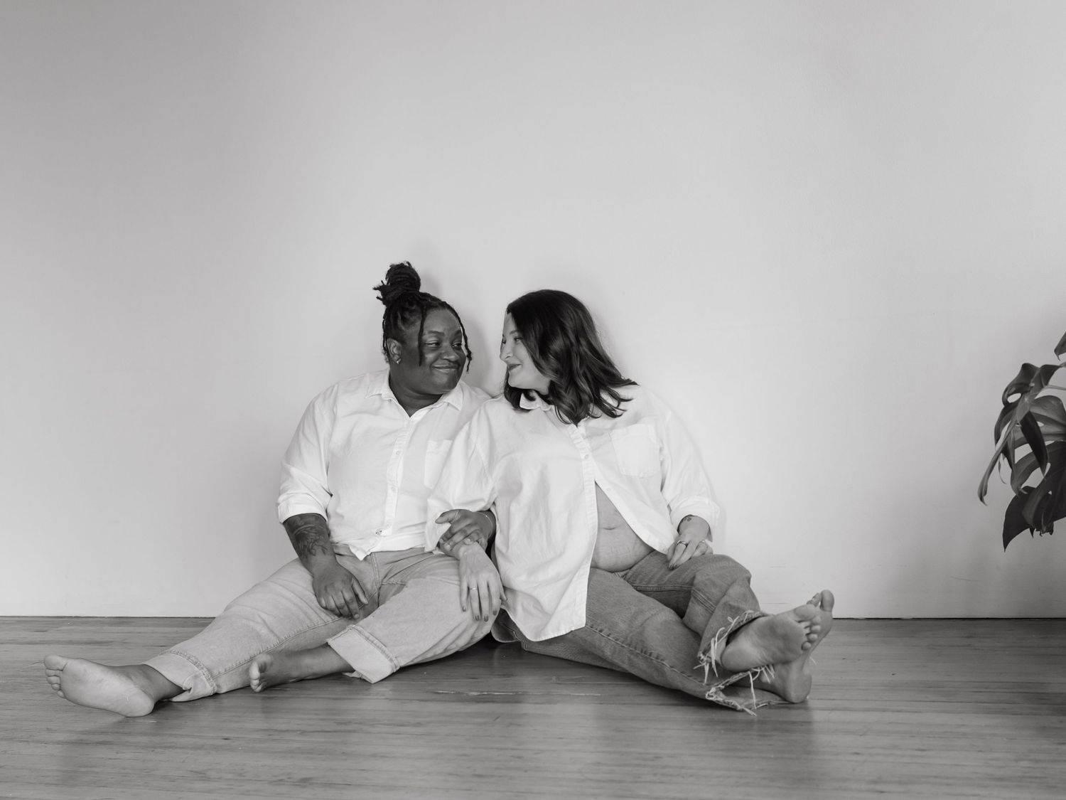 Artistic black and white photo of people sitting against a white wall.