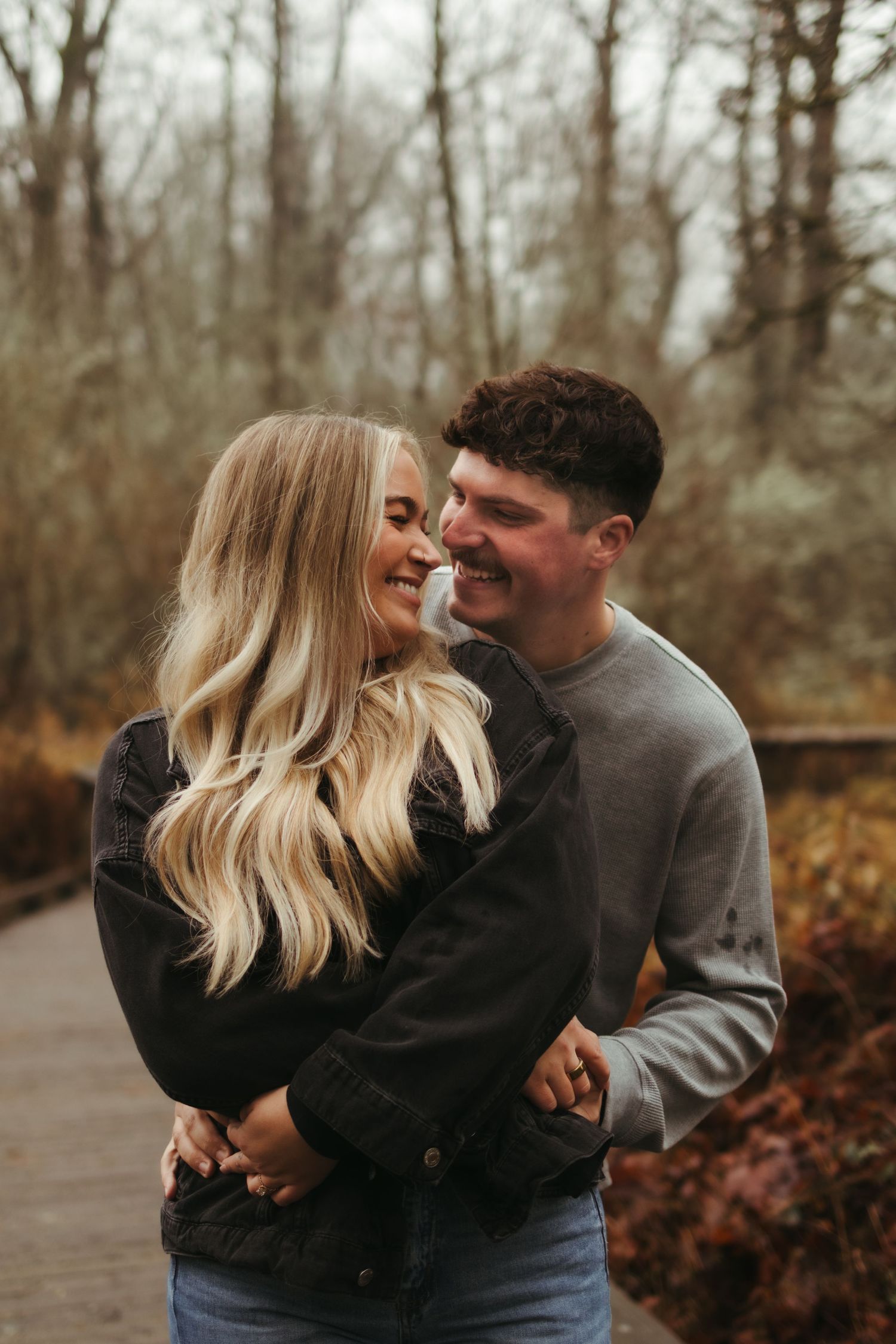 Romantic couple embracing and laughing together on a misty autumn day.