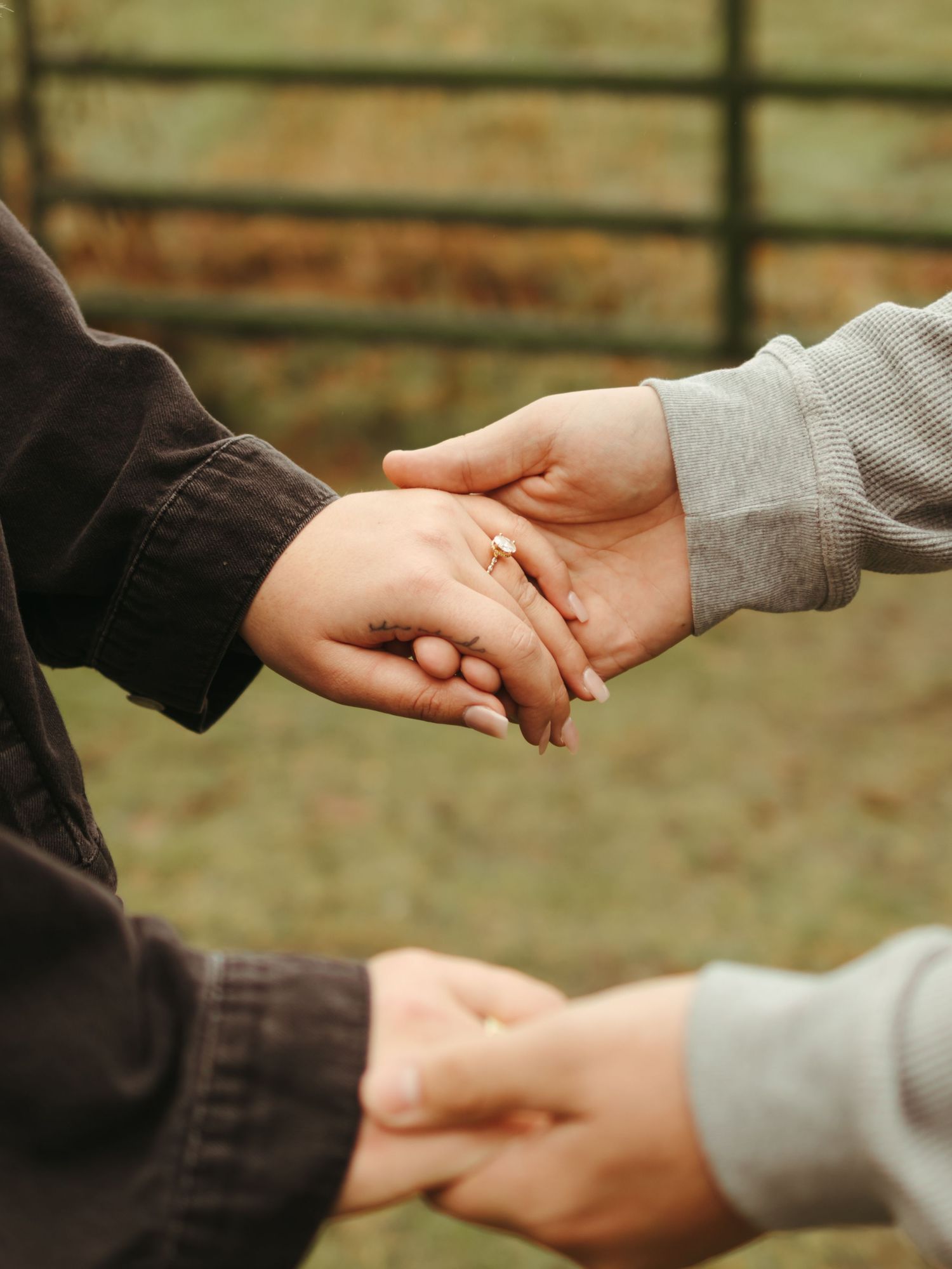 Close-up of hands tenderly touching and intertwining against natural backdrop.