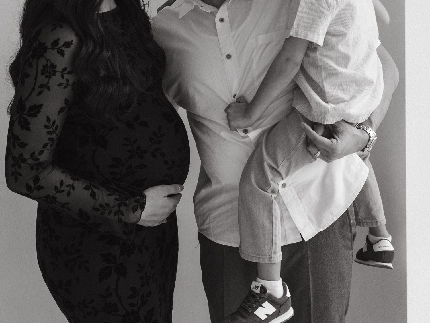 A loving family photoshoot in a bright studio with parents and child wearing coordinated outfits.