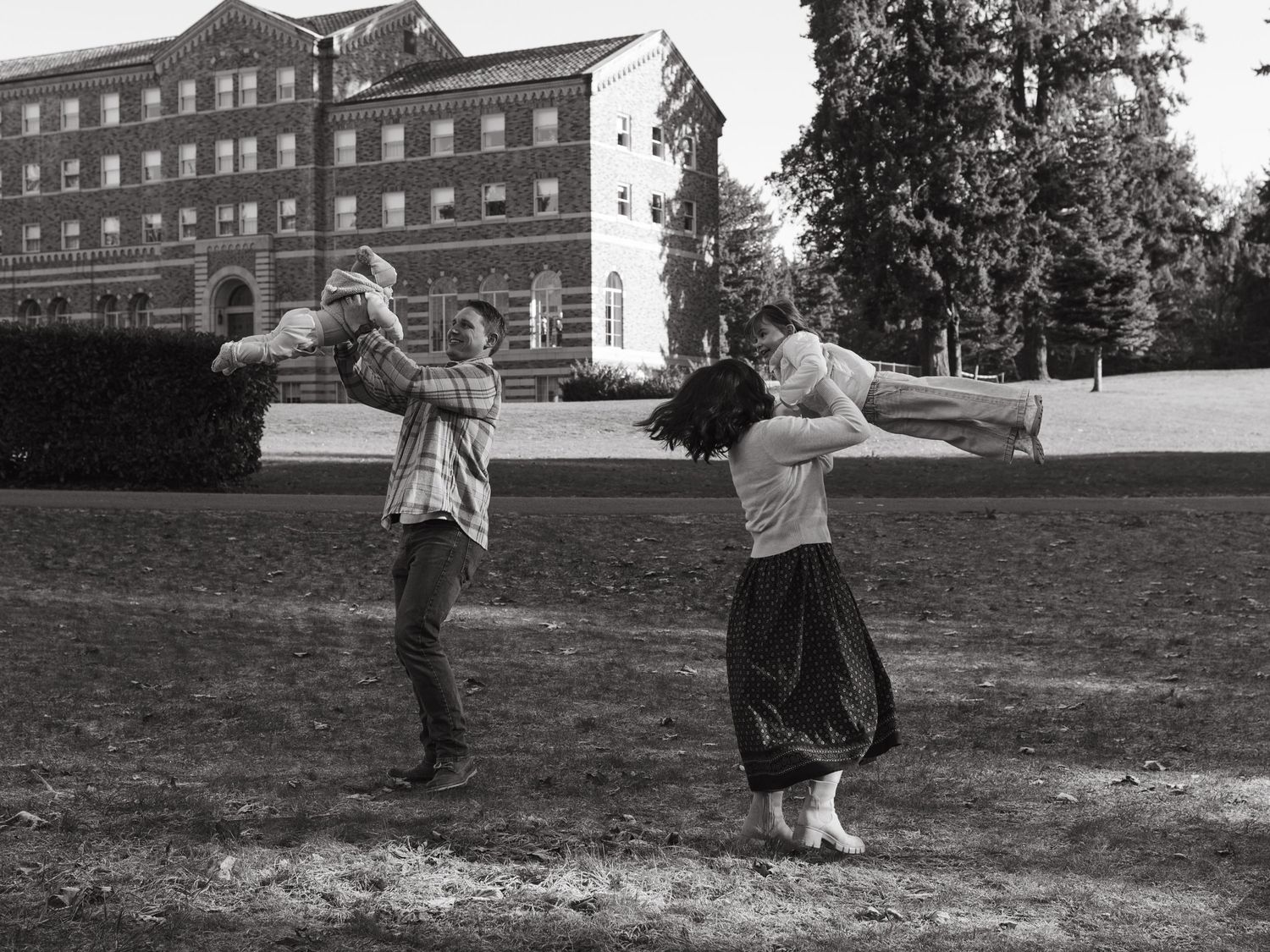Family playing and running together on a grassy hill with historic buildings in the background.