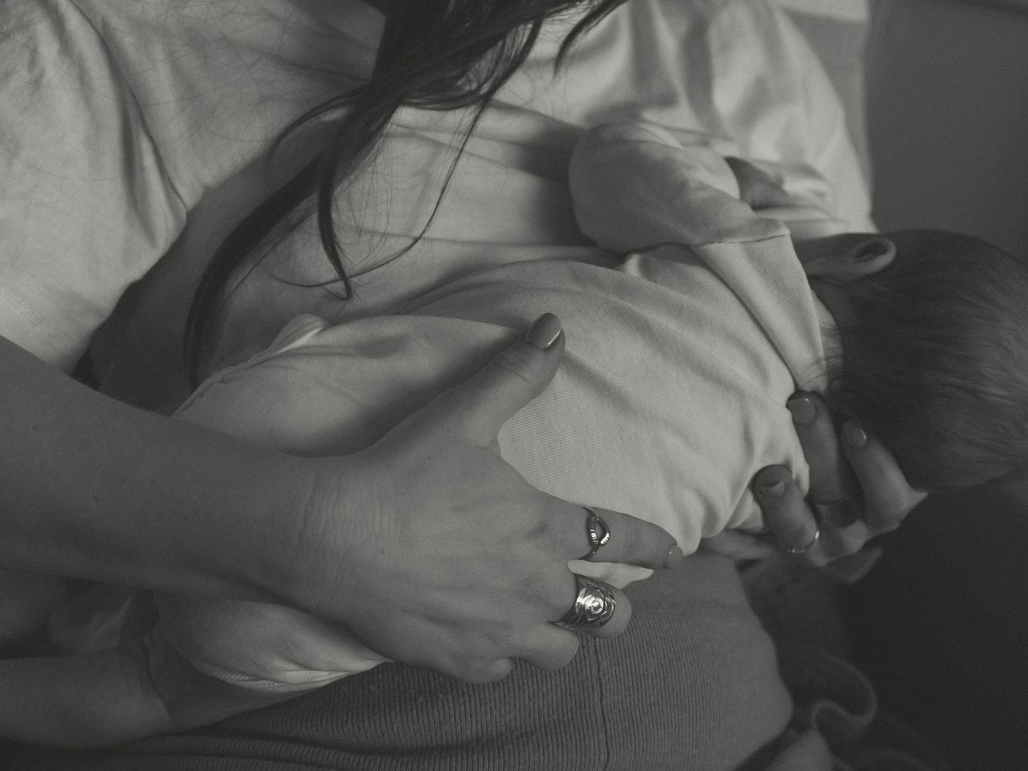 A black and white image showing gentle hands cradling a newborn.