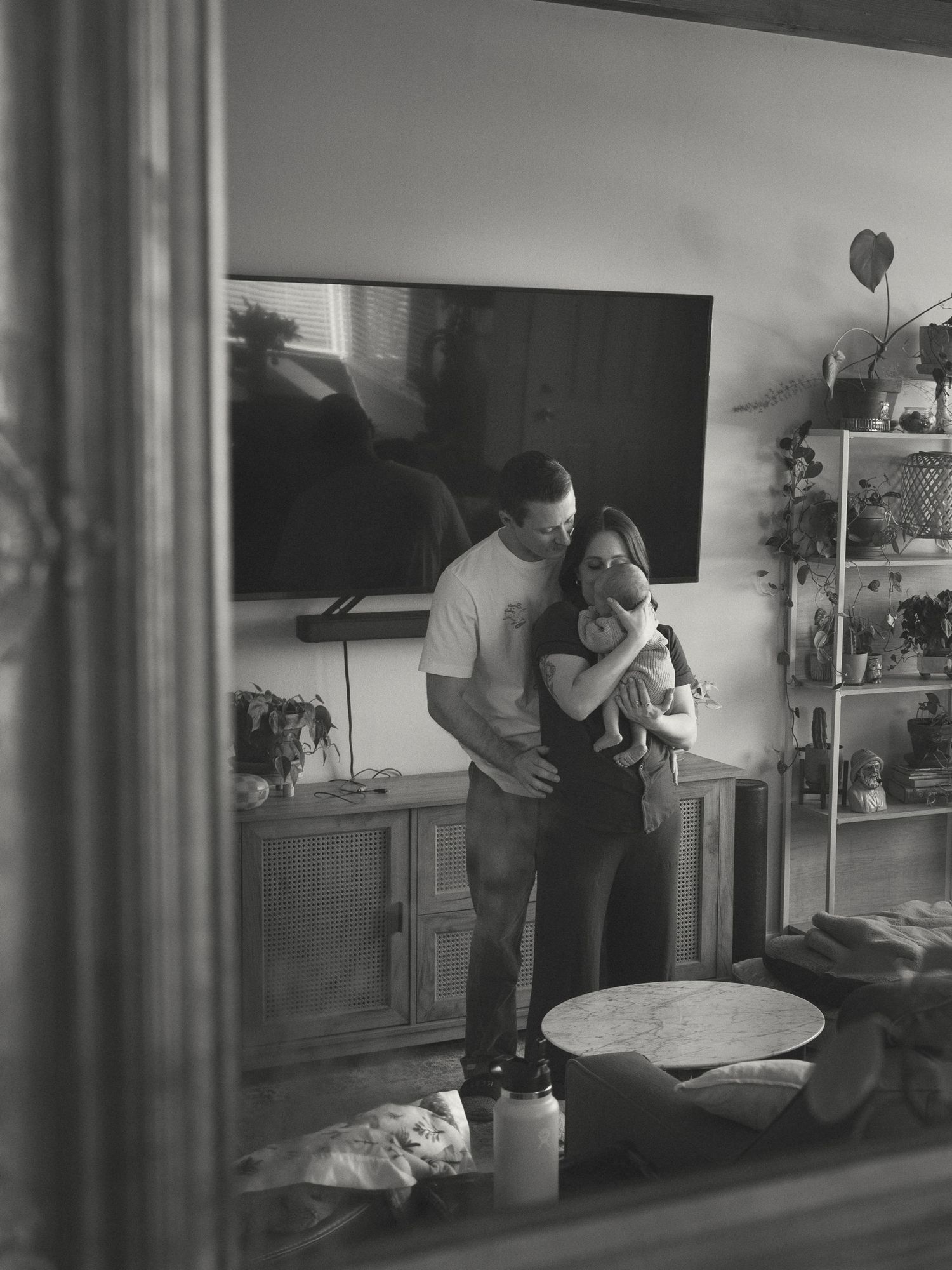 A black and white reflection in a mirror shows a tender moment at home.