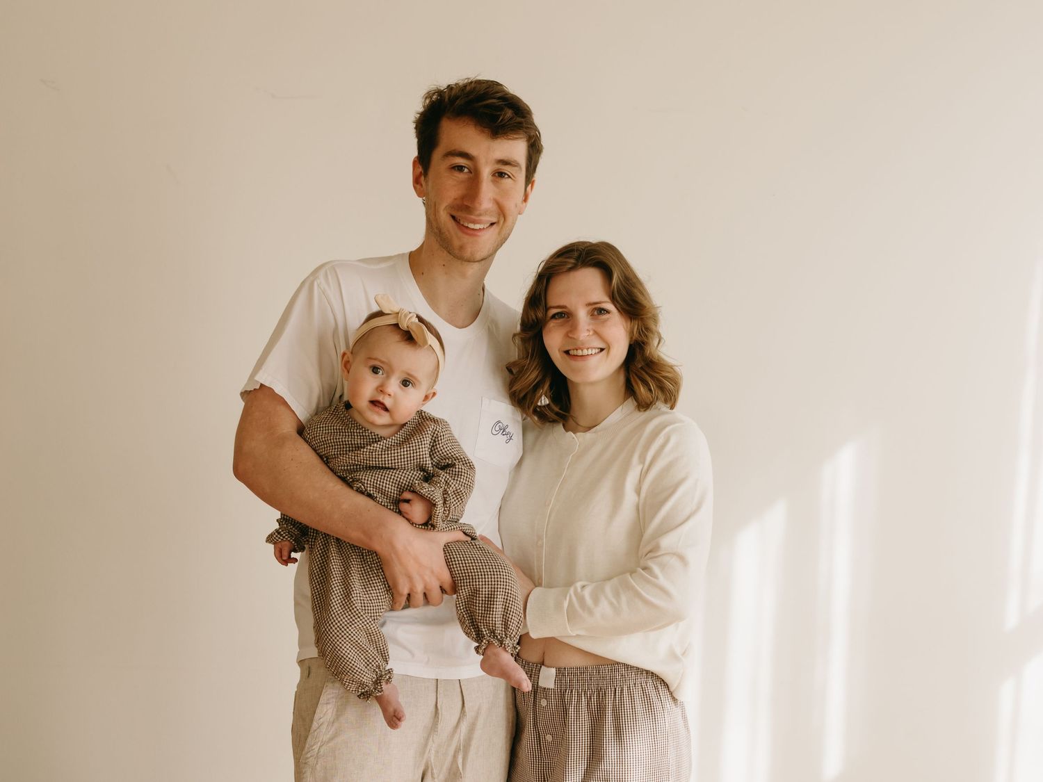 Family photo series showing tender moments against a minimalist white wall background.