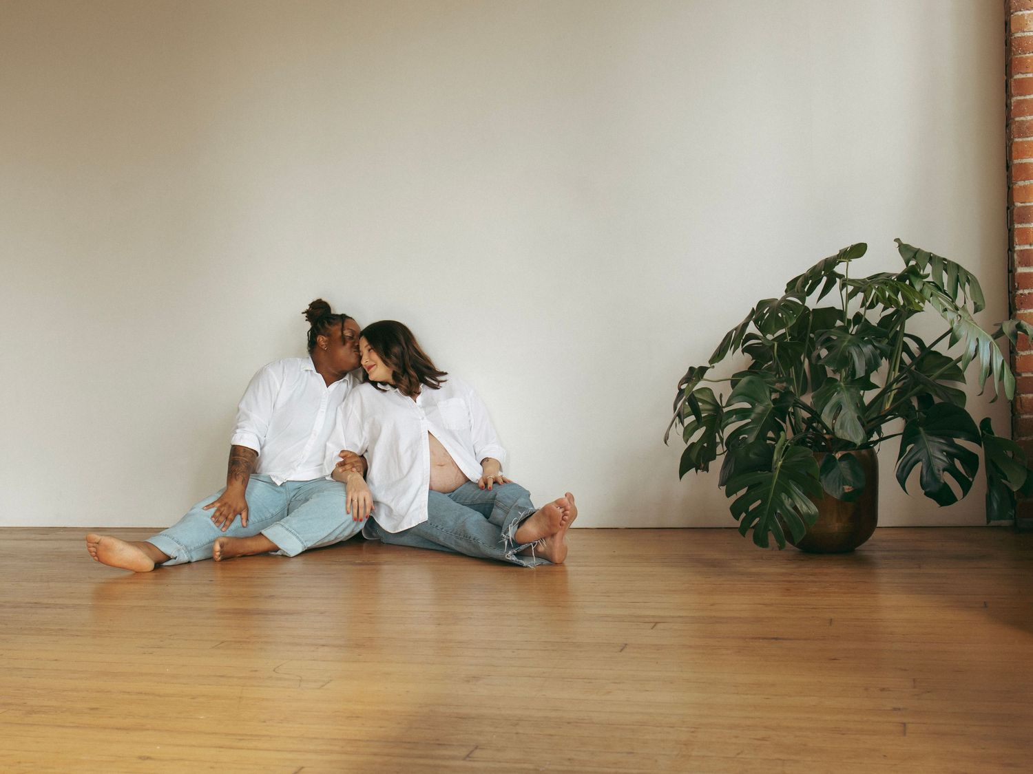 Casual photoshoot on wooden floor with minimalist decor and potted plants.
