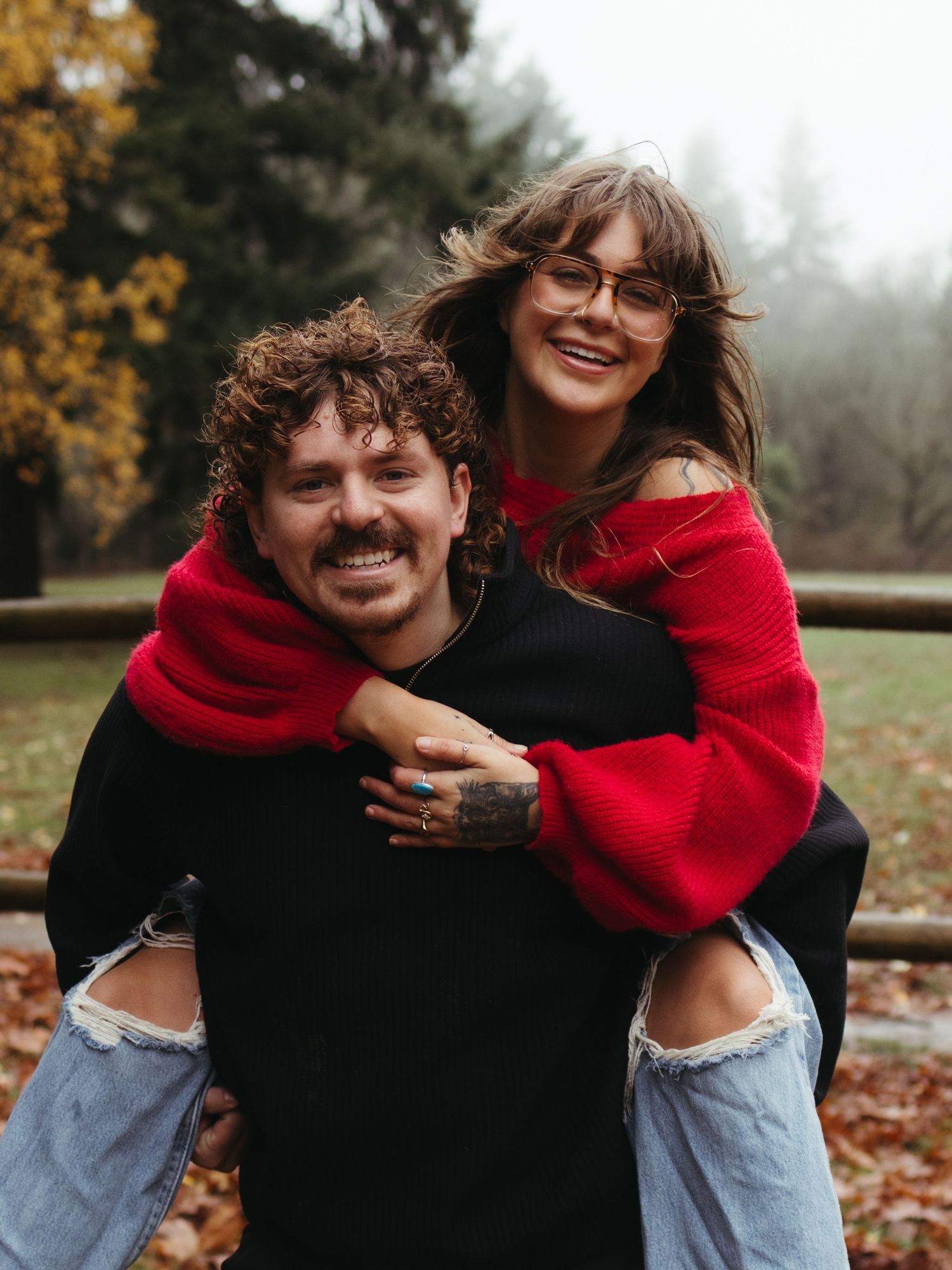 A playful couple in red and black clothing laughing together outdoors.