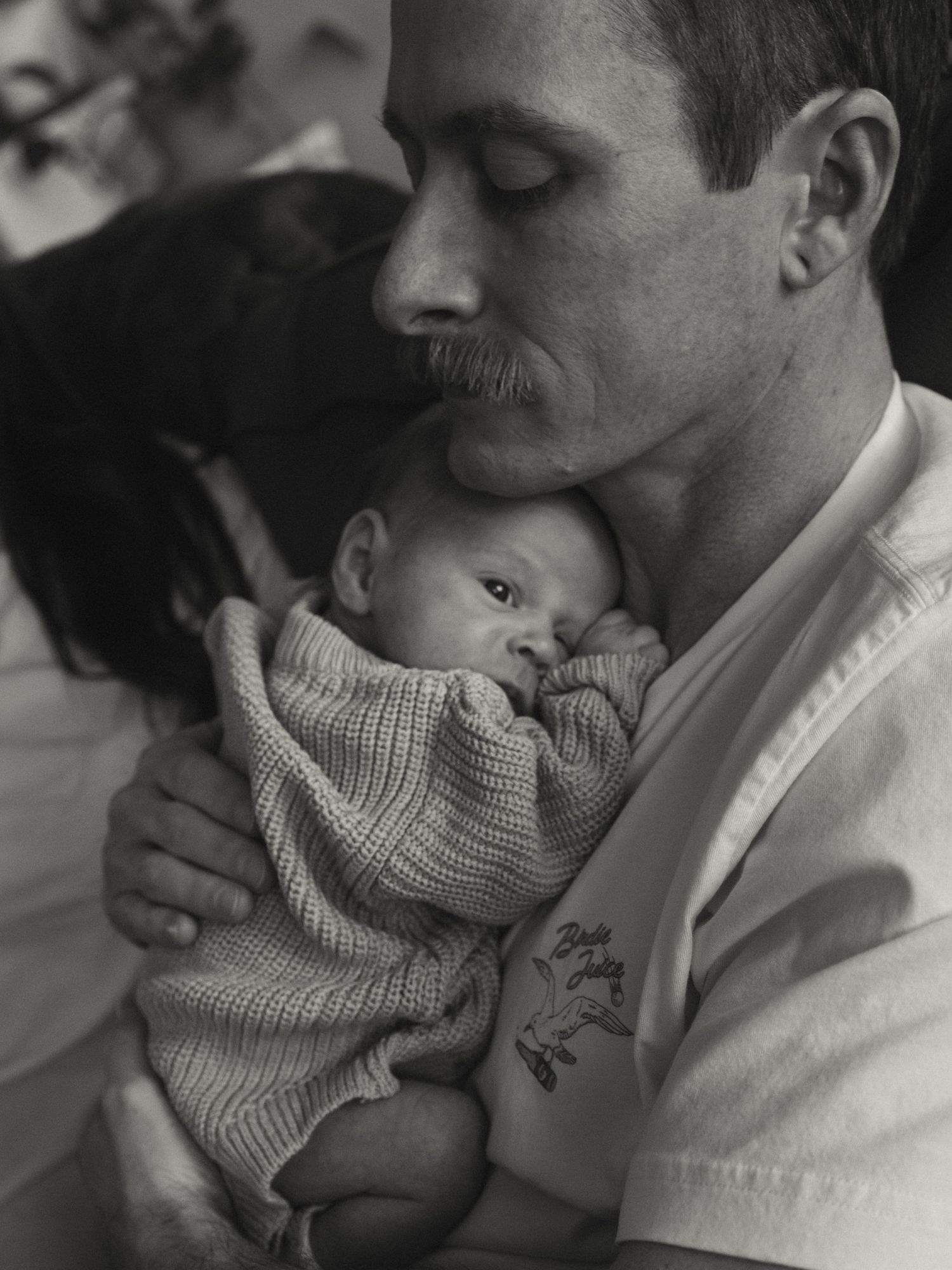 Black and white photograph showing intimate bonding moment between parent and baby.