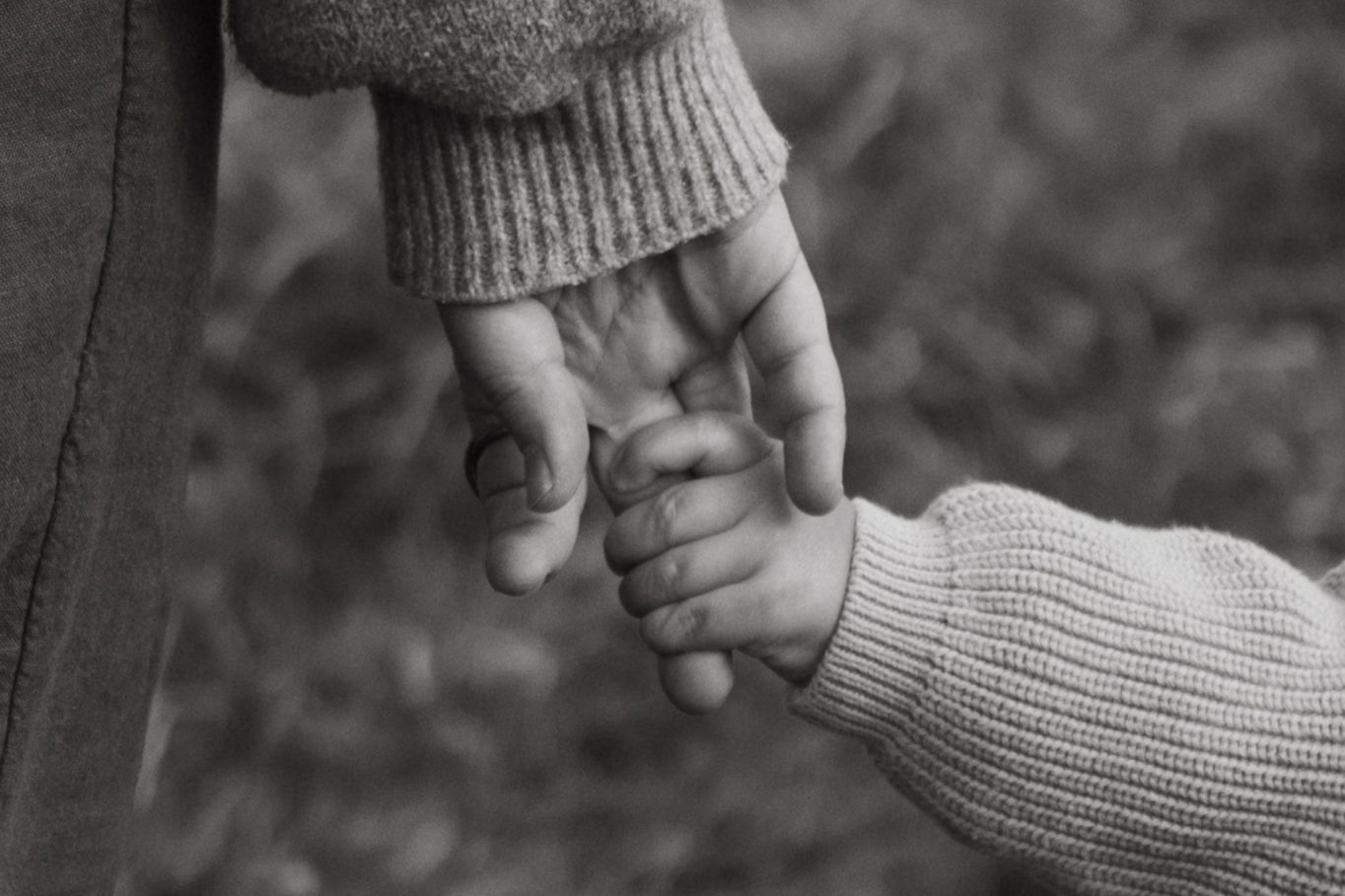 A black and white image showing two hands clasped together in a loving grip.