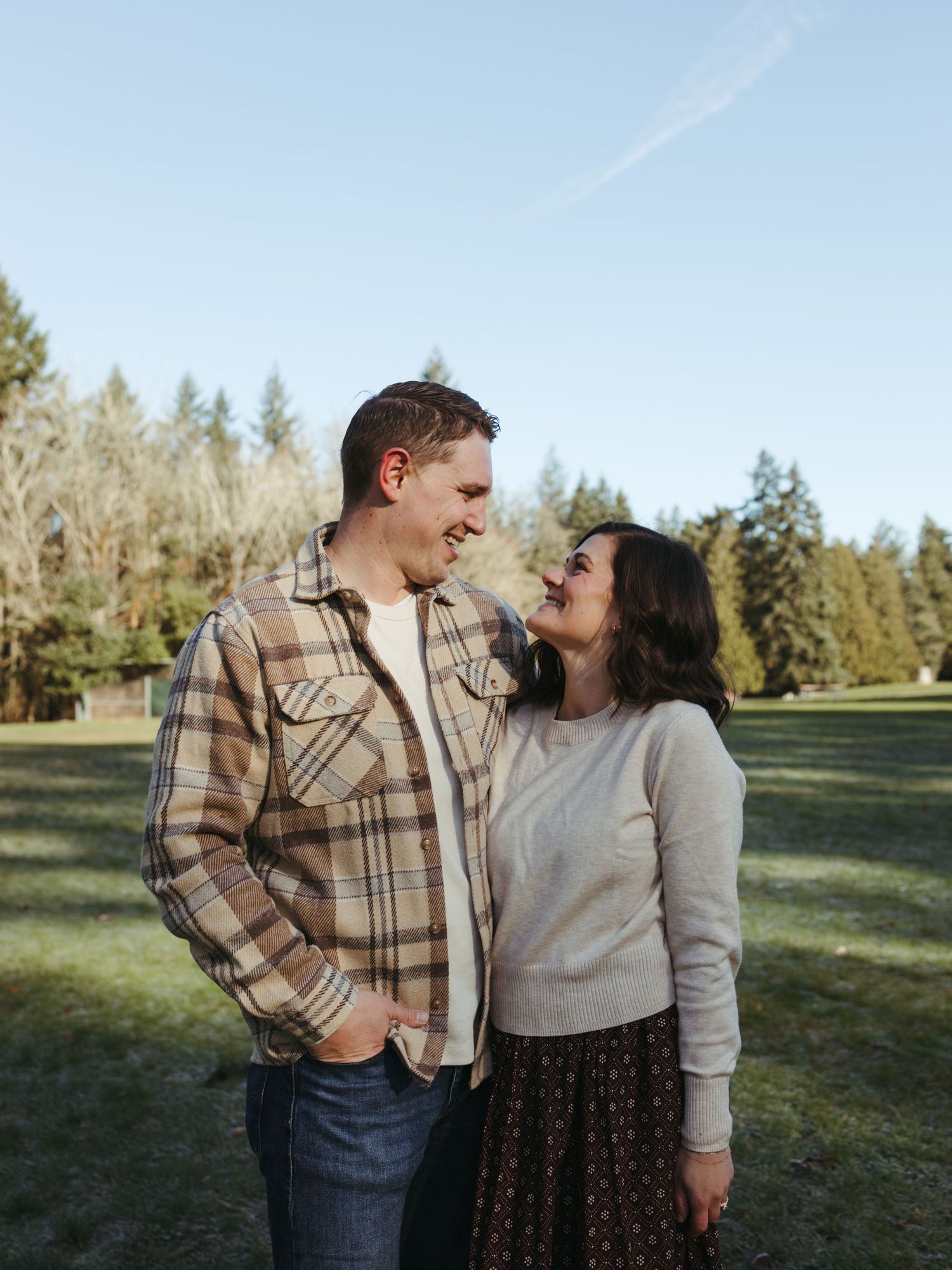 Couple sharing playful and romantic moments in a sunny outdoor field setting.