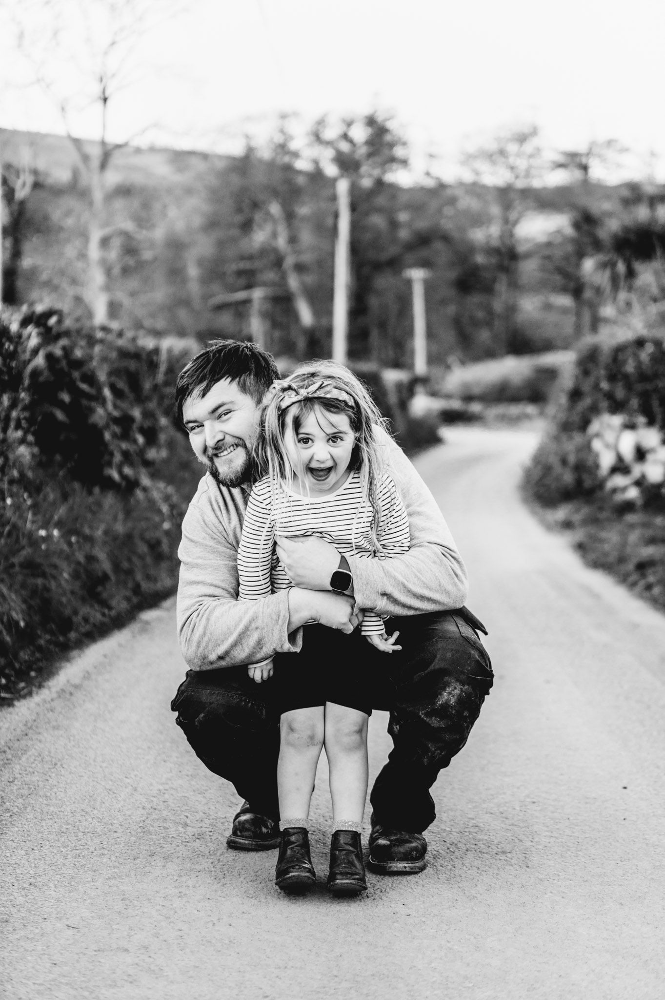 Playful black and white sequence of people crouching and laughing on a country road.