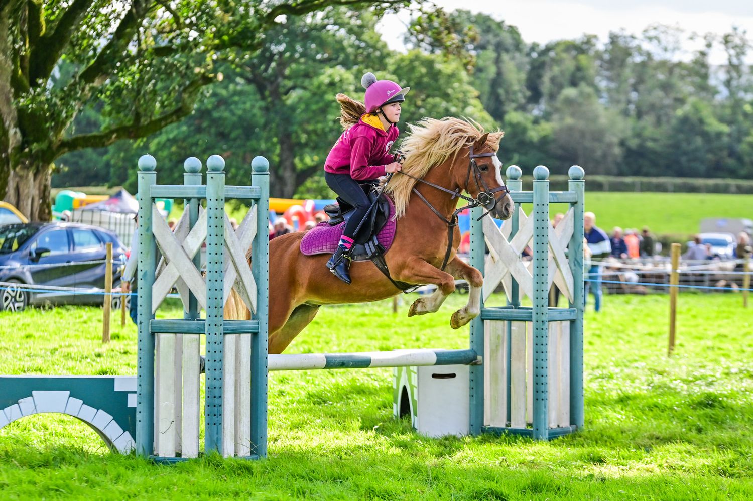 Horses jumping over colorful obstacles during an outdoor equestrian competition.