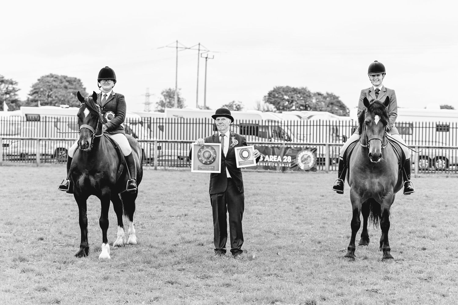 Wide view of horses and handlers positioned in a row at an outdoor equestrian competition.