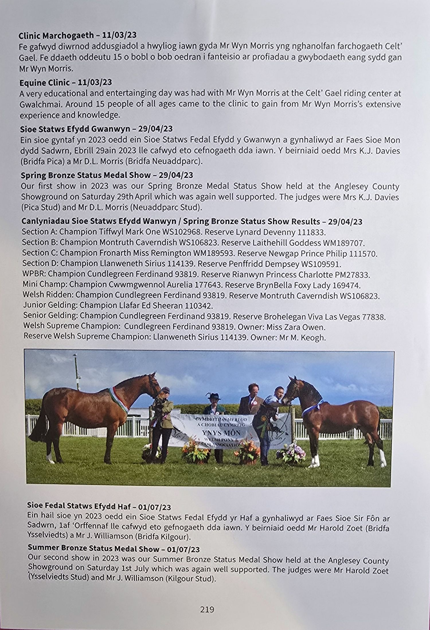 A row of horses and handlers stand in a grassy field with text documents visible in the background.