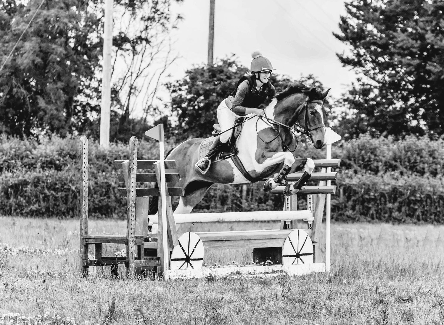 Black and white sequence showing equestrian jumping over obstacles at a competition.