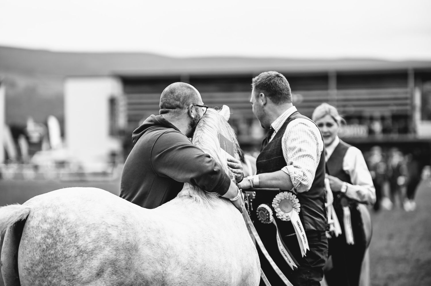 Black and white equestrian show jumping competition with riders navigating obstacles on a grass field.