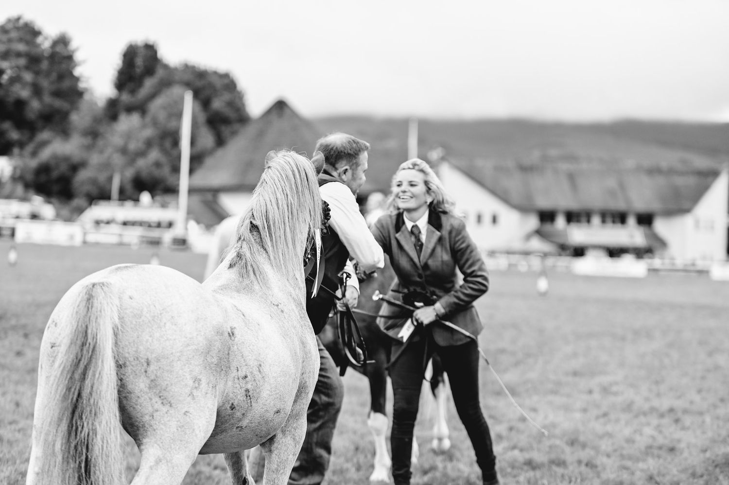 Black and white photograph of horses and handlers lined up at an outdoor equestrian show.