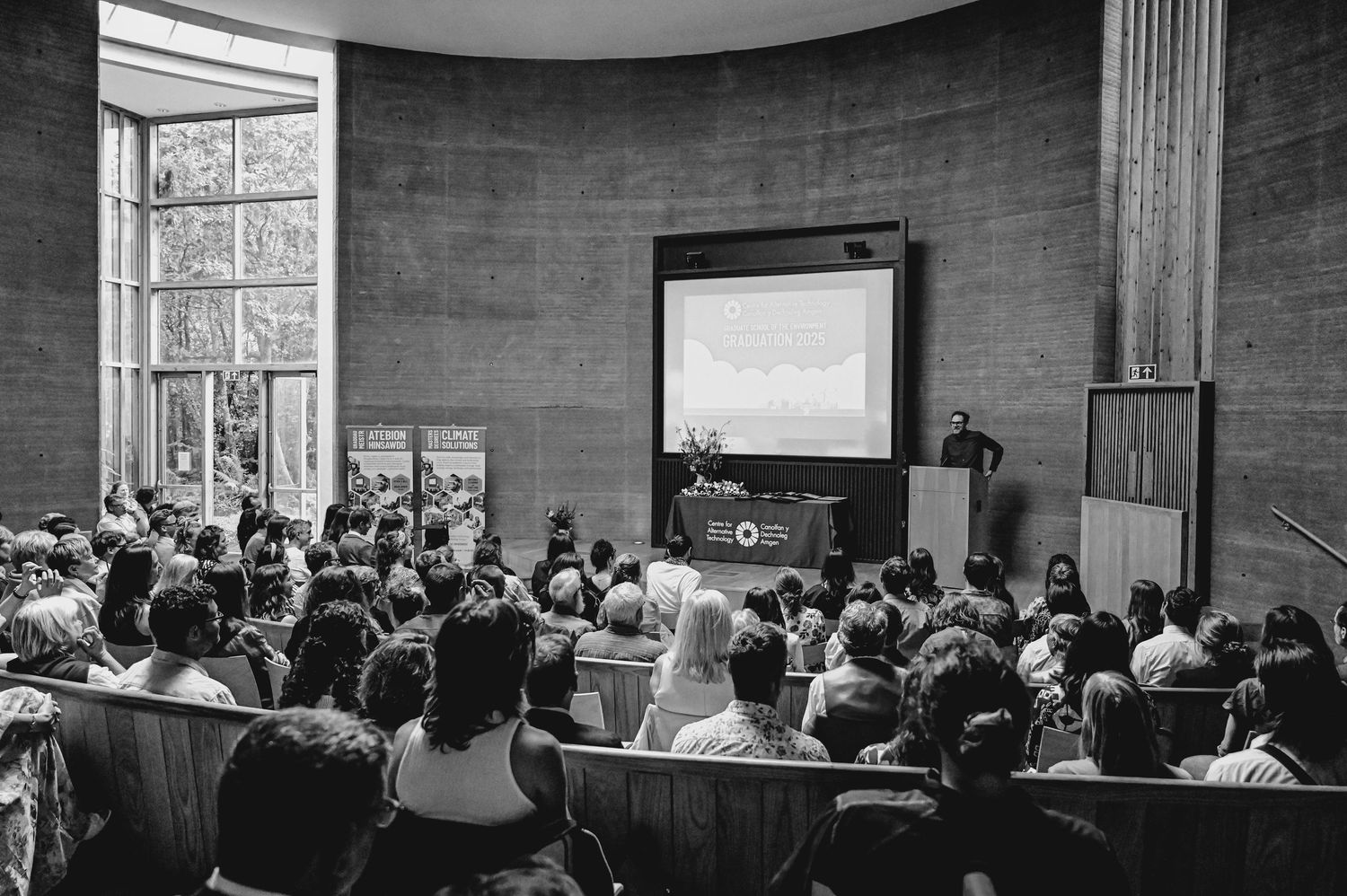 Large audience seated in curved auditorium during presentation or lecture.