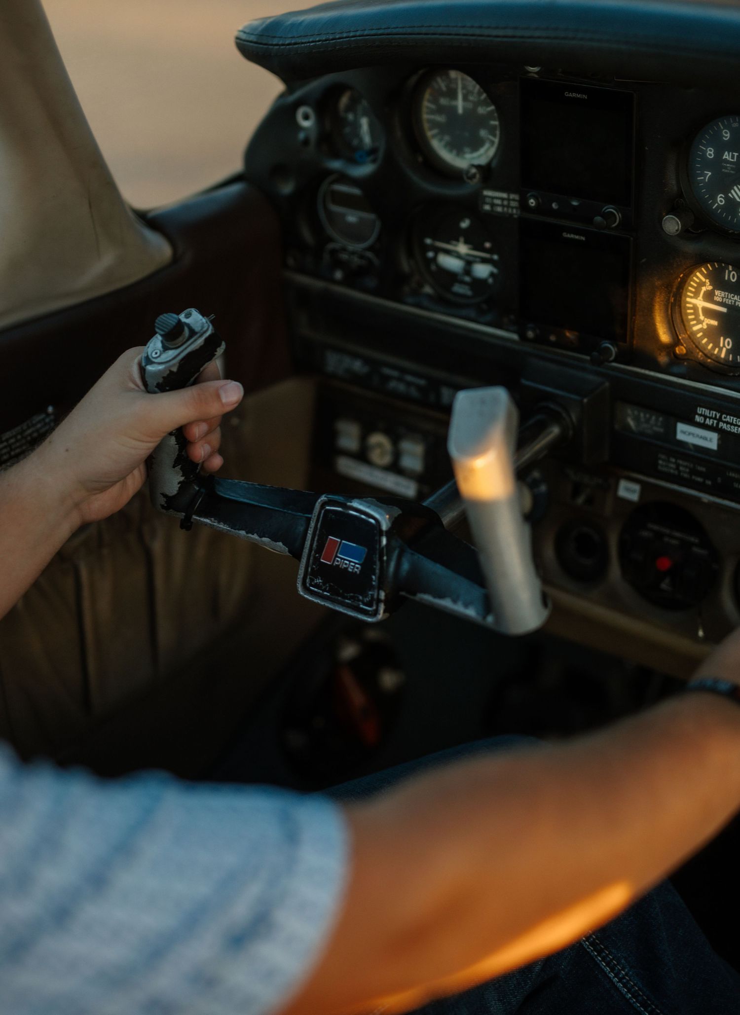 Close-up of a pilots hand holding a key near the ignition of a small aircraft instrument panel.