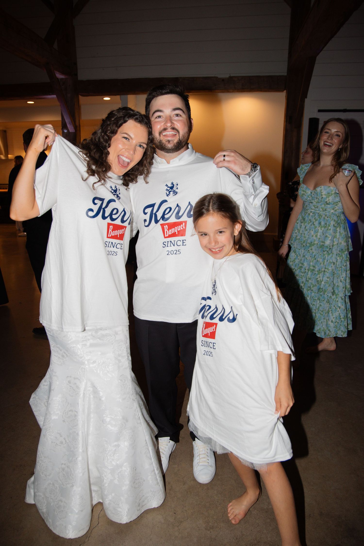 A bride, groom, and young girl pose proudly in matching Kerrs since 2025 custom wedding t-shirts.