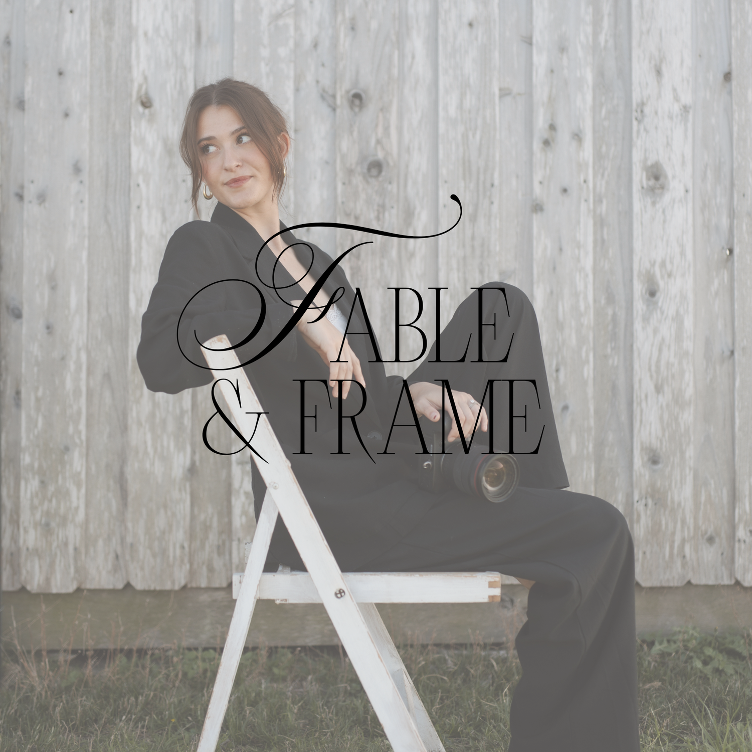 Woman in black suit sitting on white chair against wooden fence with Fable and Frame logo overlay.