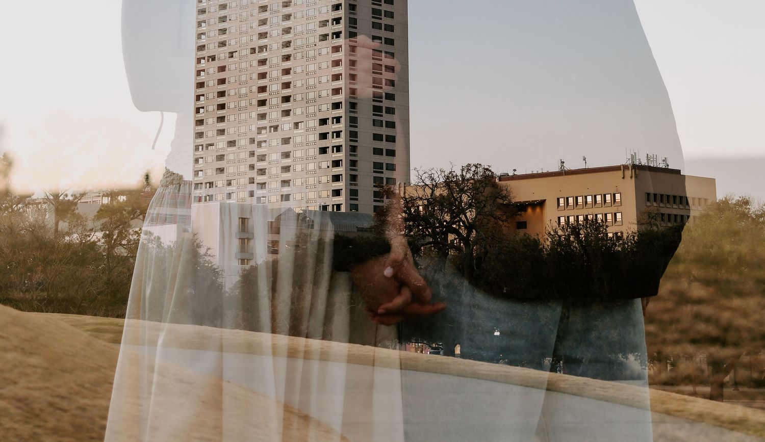 Creative double exposure photo blending a couple kissing with urban cityscape and high-rise building.