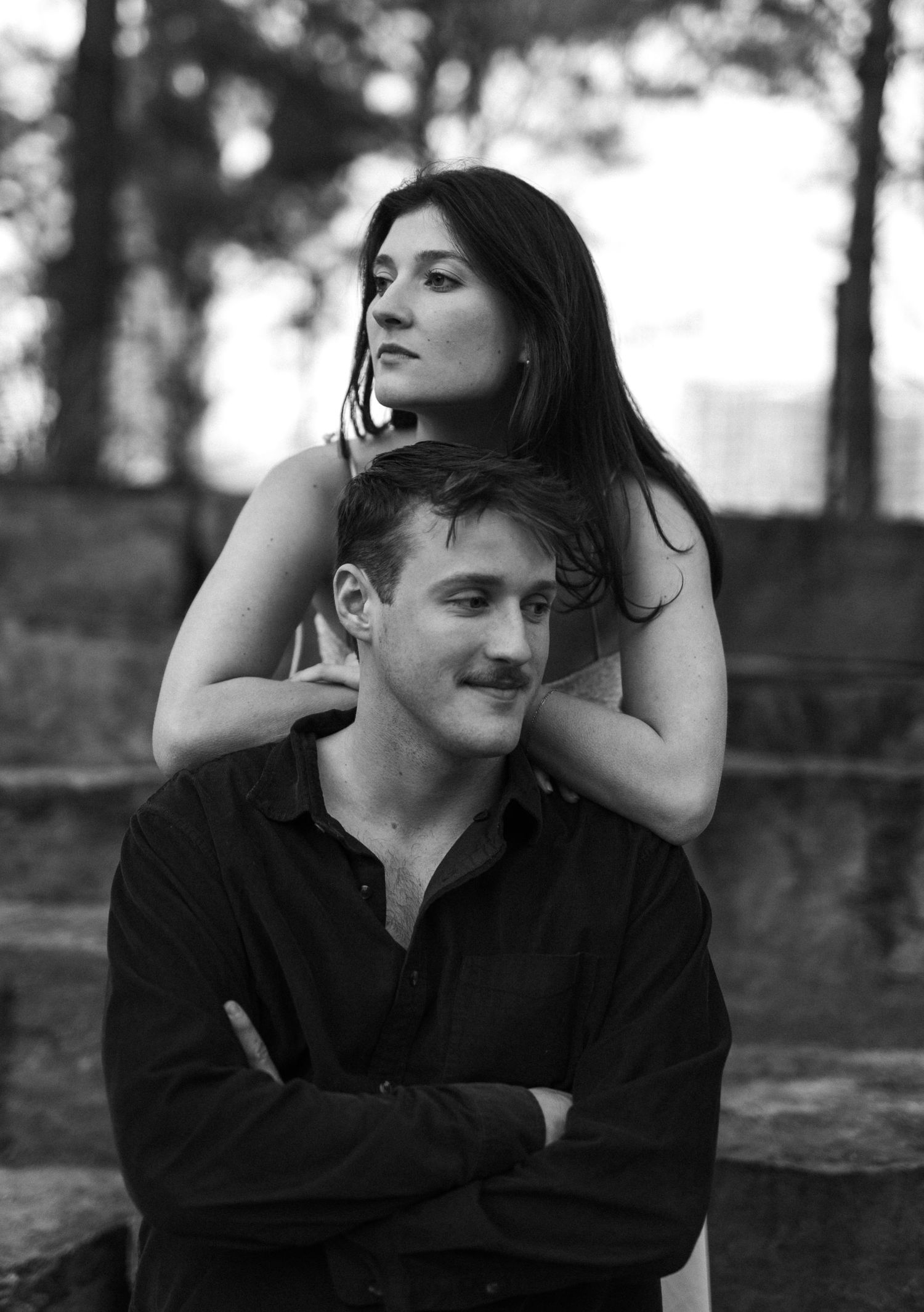 Black and white portrait of an engaged couple posing near stone steps outdoors.