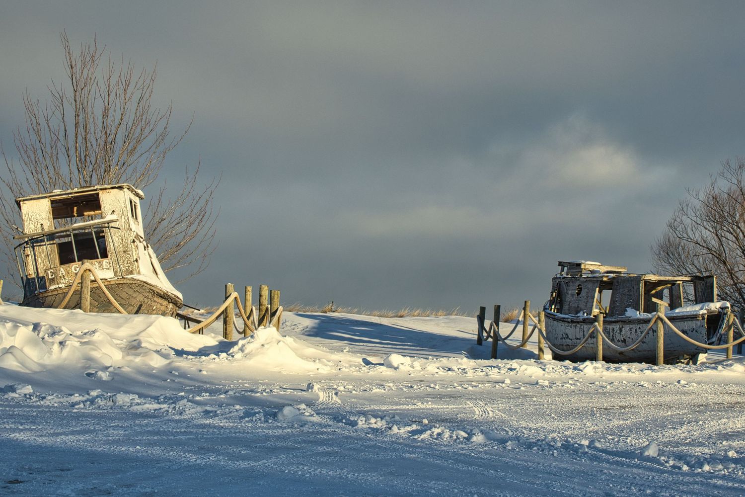 Snow-covered harbor with abandoned commercial fishing boats under a dramatic winter sky in Northern Wisconsin