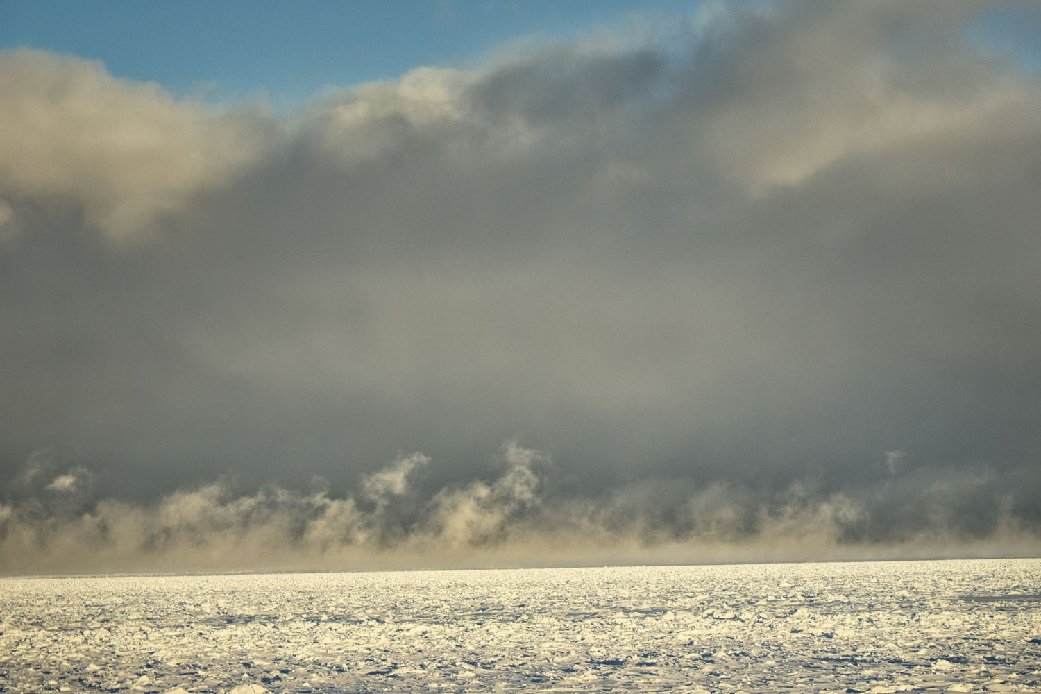 Low winter clouds rolling over a frozen Lake Superior in Northern Wisconsin, captured as a dramatic fine art photograph.