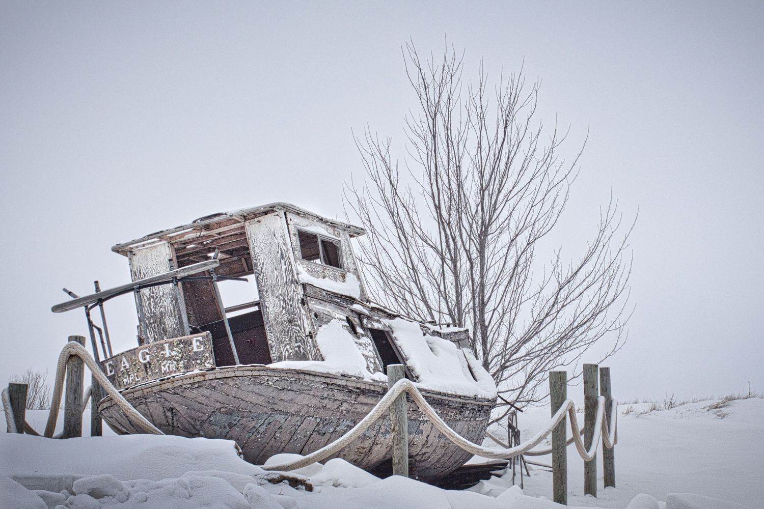 Abandoned commercial fishing boat covered in snow along a winter shoreline in Northern Wisconsin
