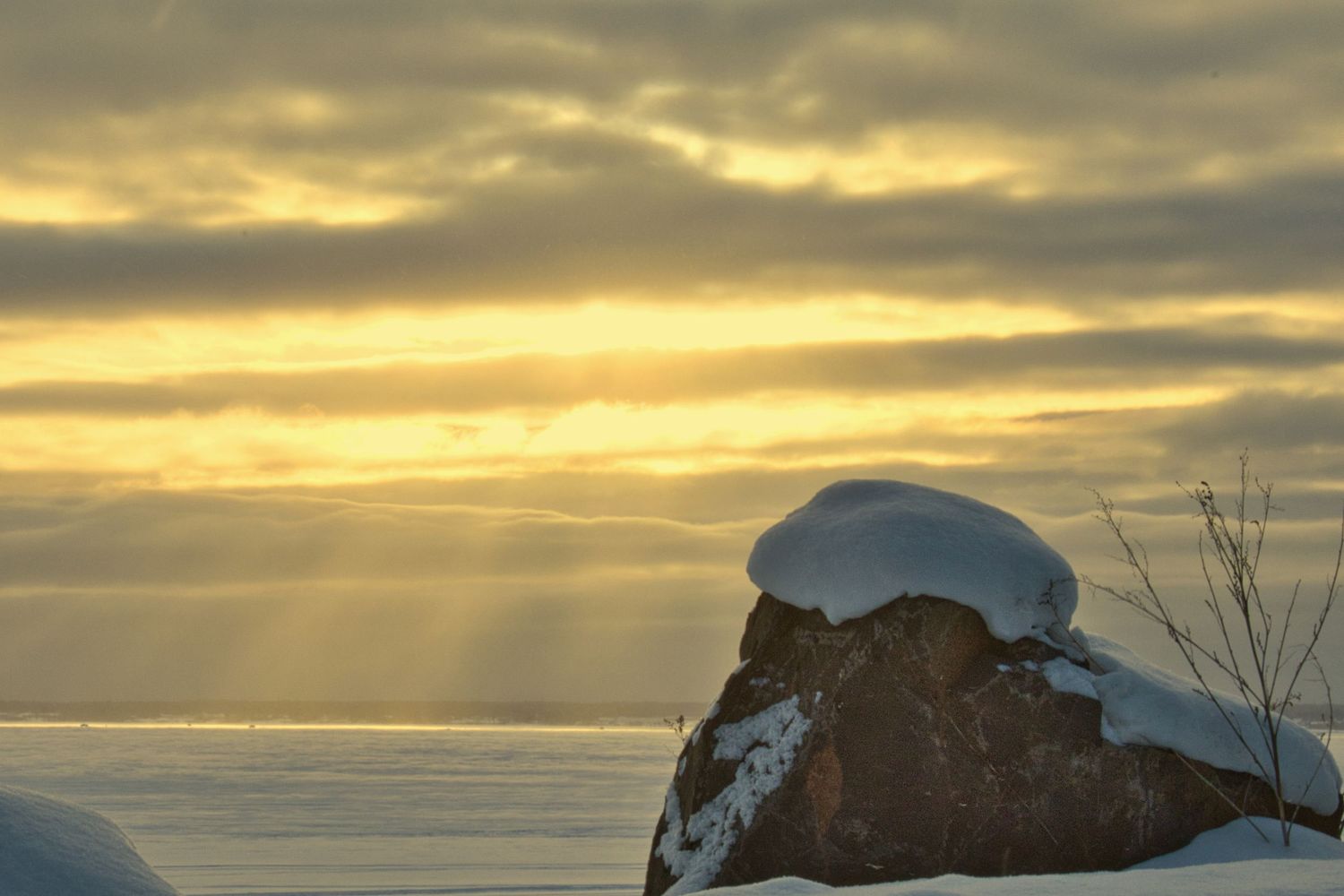 Golden winter sunrise over frozen Chequamegon Bay with snow-covered shoreline in Northern Wisconsin.