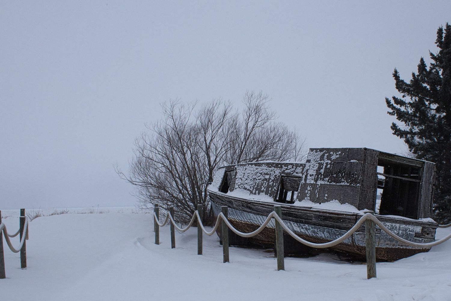 Snow-covered commercial fishing boat resting along a winter shoreline in Northern Wisconsin.
