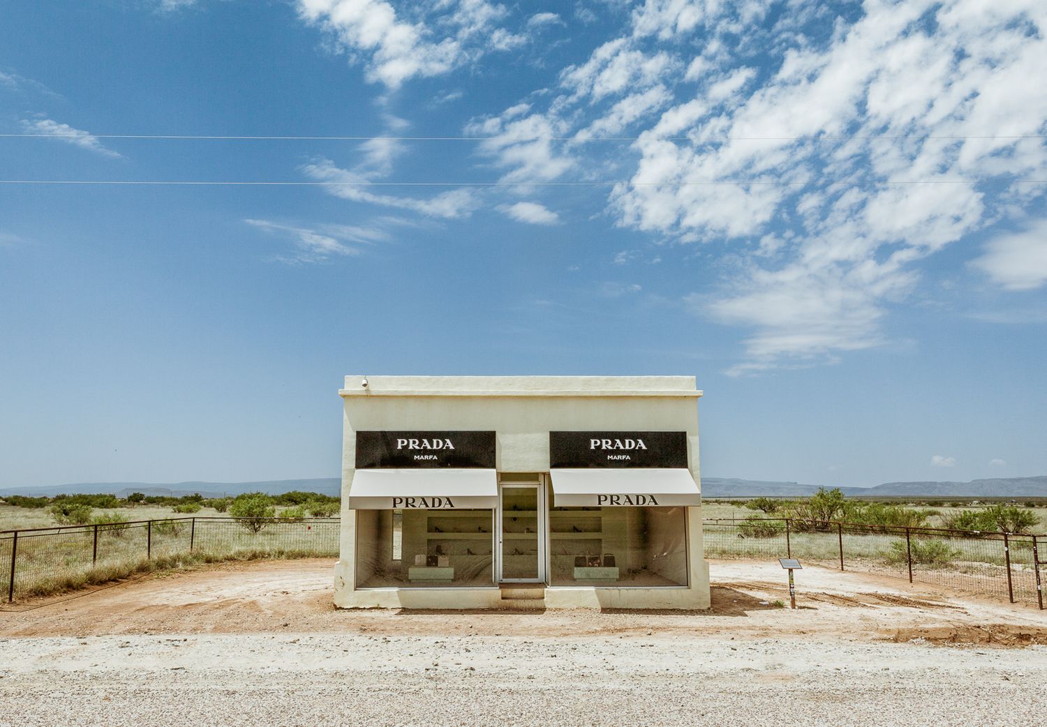 Row of minimalist white buildings against blue sky in desert landscape.