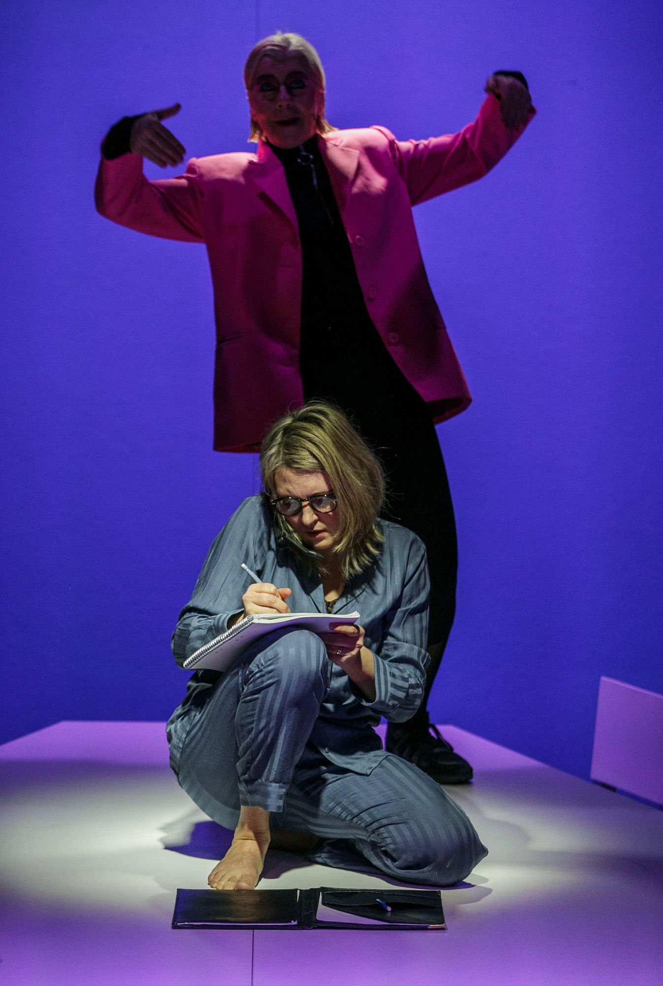 A performer in denim on a purple-lit stage performing an expressive sequence.