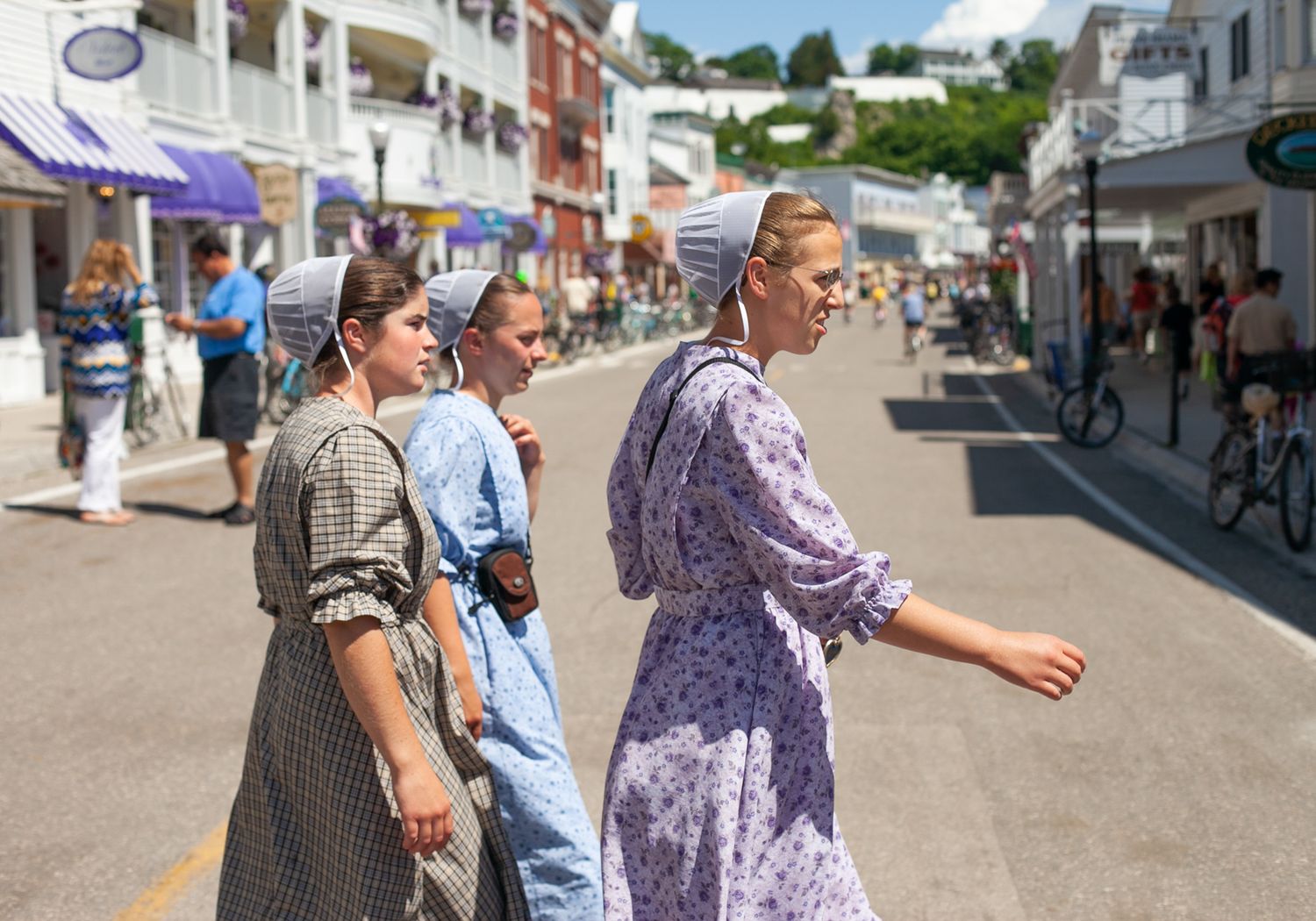 People walking along a busy small-town main street with shops and businesses.