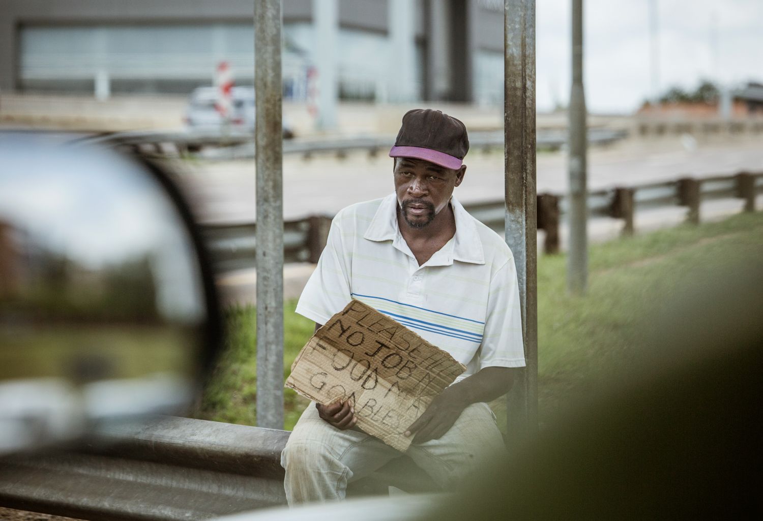 Person reading a newspaper while sitting outdoors on a sunny day.