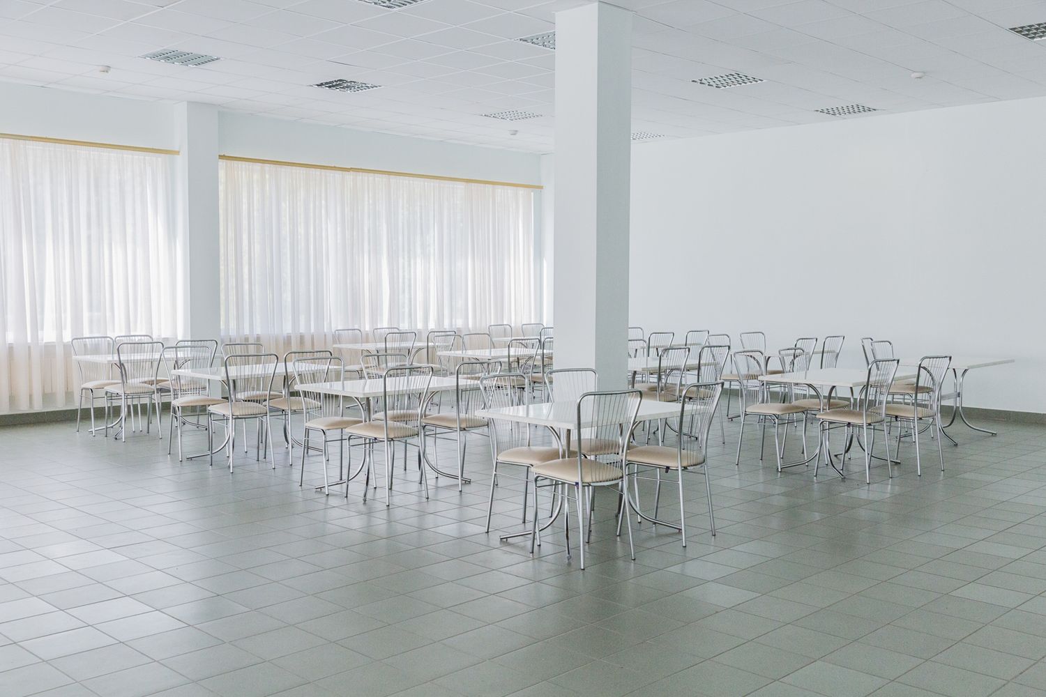 Empty conference room with white chairs arranged in rows and white curtains.