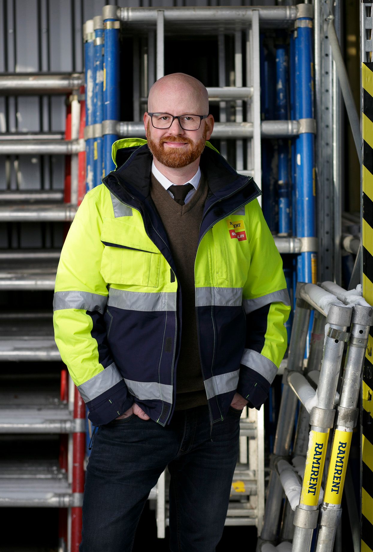 Industriarbetare med synlig skyddsutrustning och glasögon poserar nära byggnadsställning