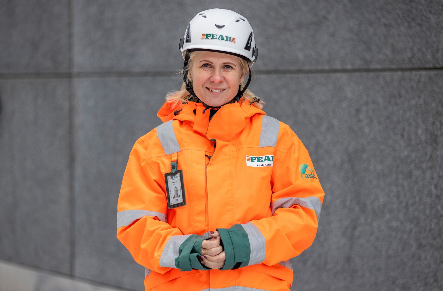 Arbetare i ljus orange säkerhetsutrustning och hjälm som arbetar i en industriell miljö