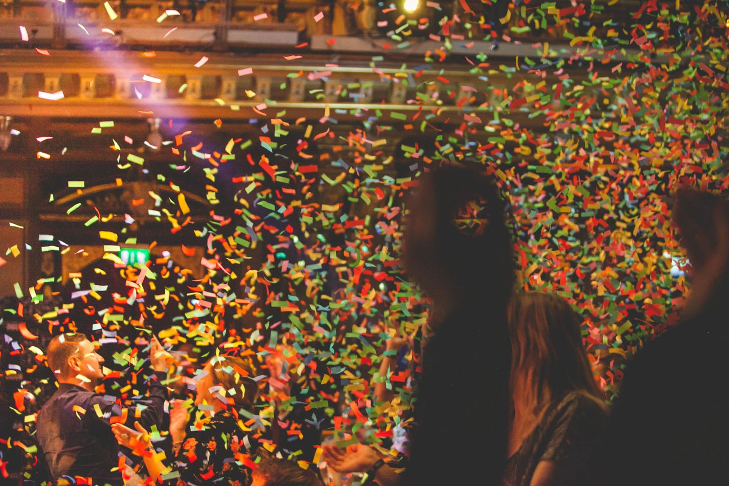 Colorful confetti falling against dark background with ambient lighting.