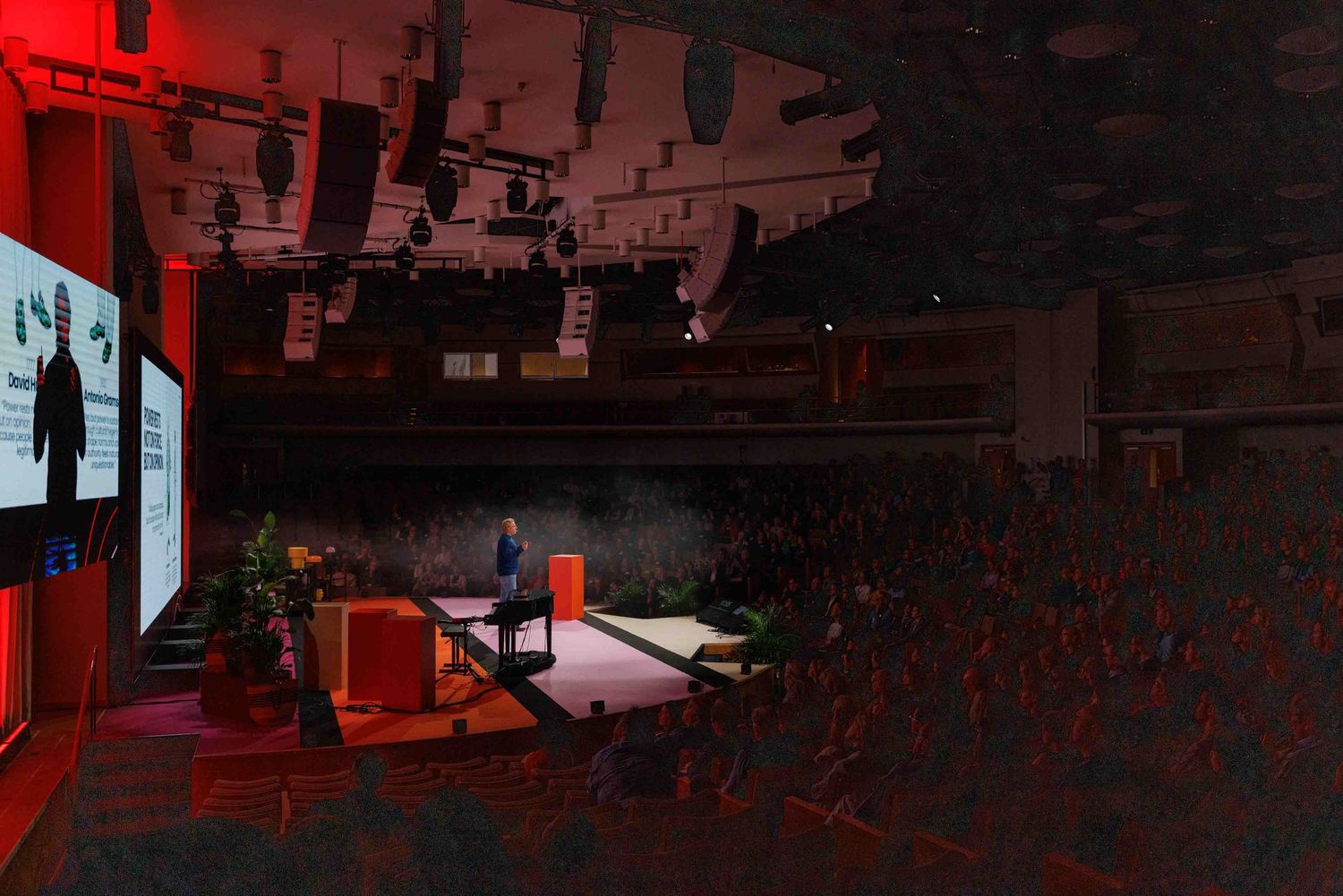 An event venue with dramatic red lighting and technical equipment visible.