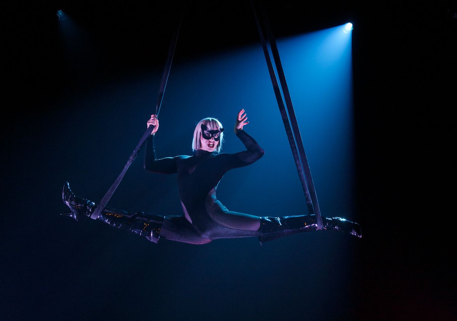 Performers in dramatic poses against a dark stage with blue lighting effects.