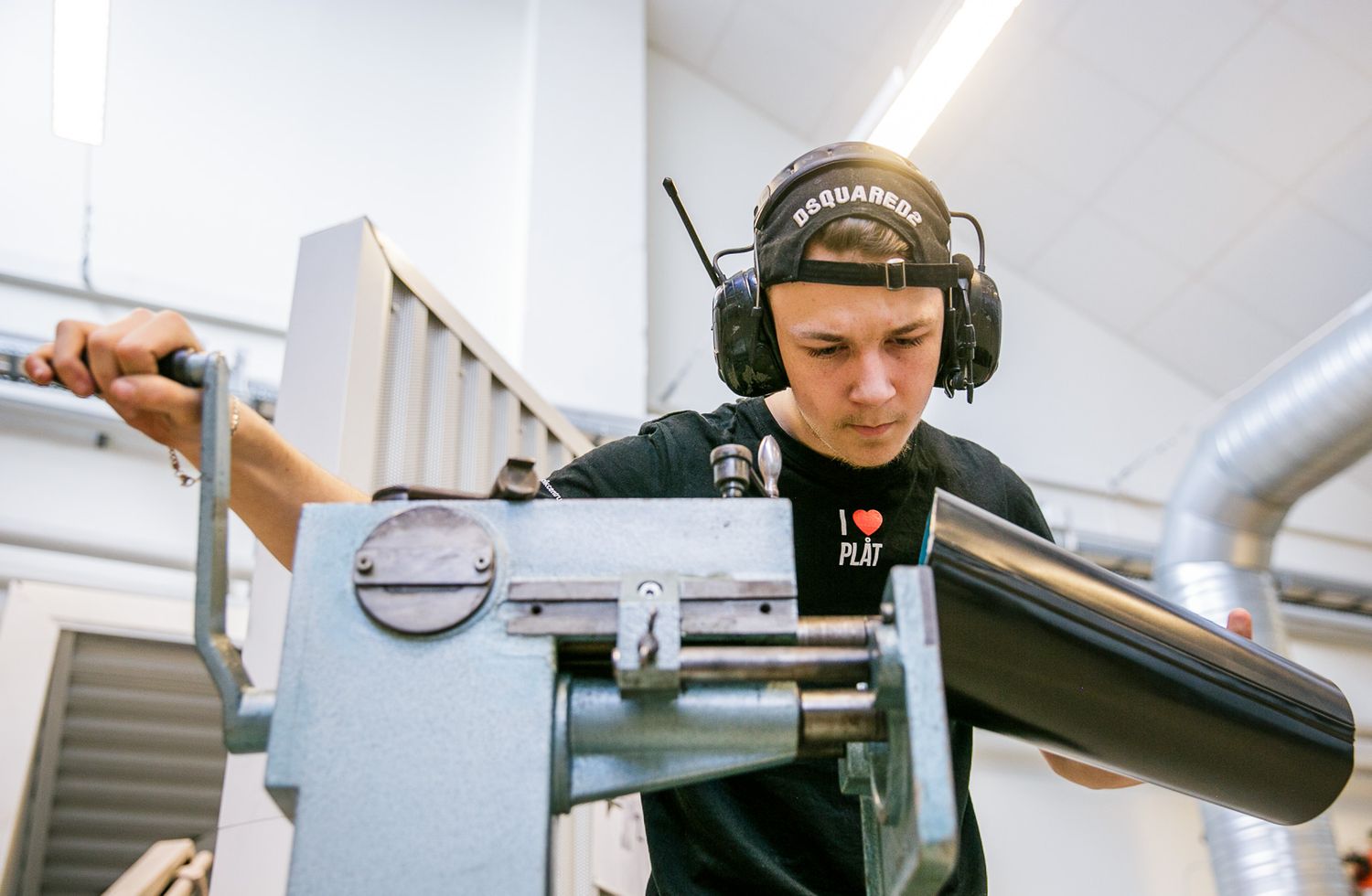 Person wearing protective headgear working with precision tools in manufacturing facility.