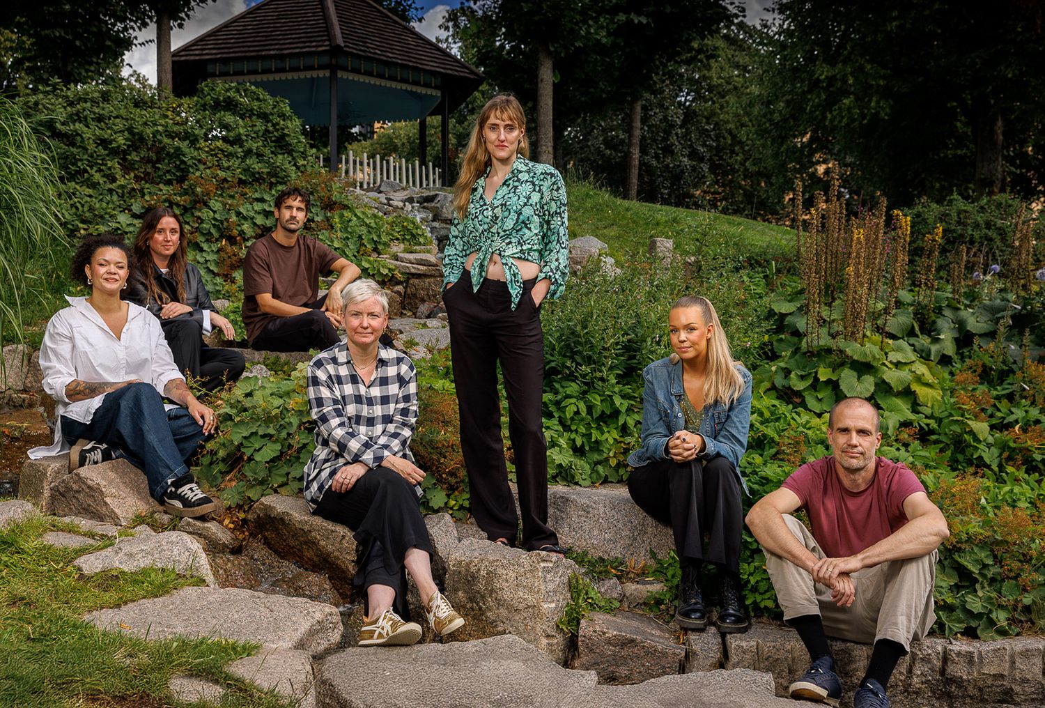 People sitting on rocks in a lush garden setting.
