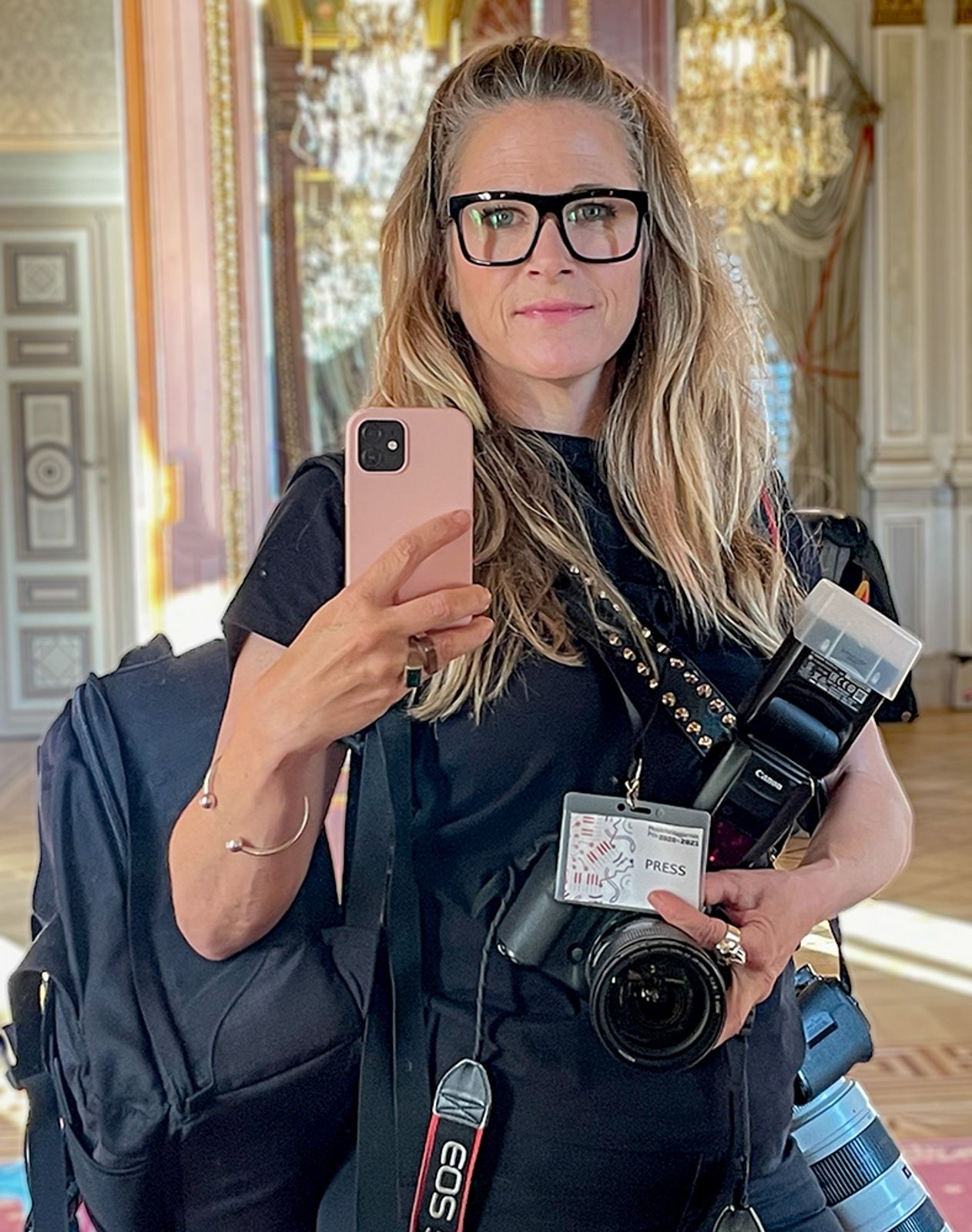 Professionell fotograf i svarta kläder som visar kamerautrustning i ett utsmyckat rum