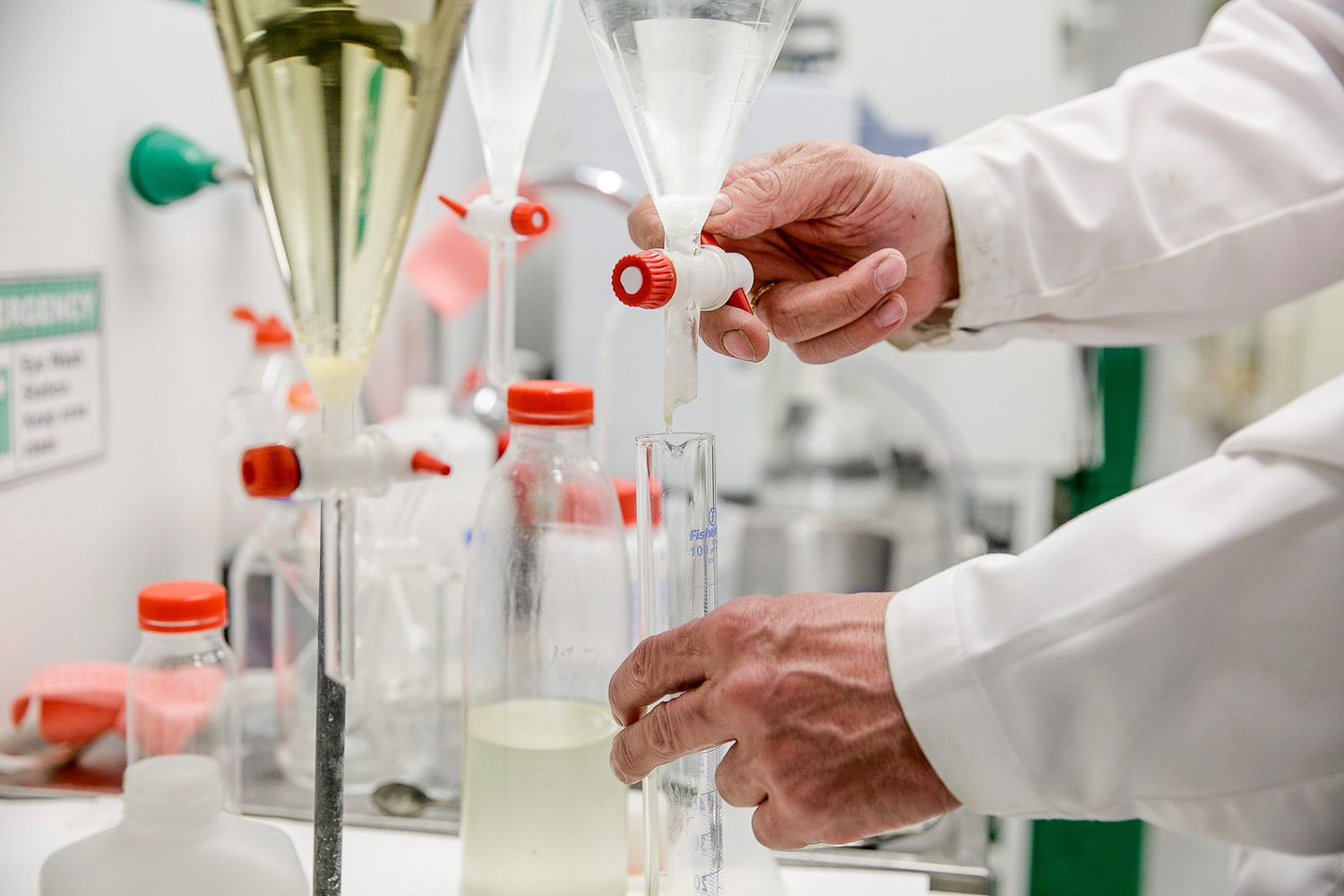 Laboratory scientist in white coat handling test tubes and chemical samples.