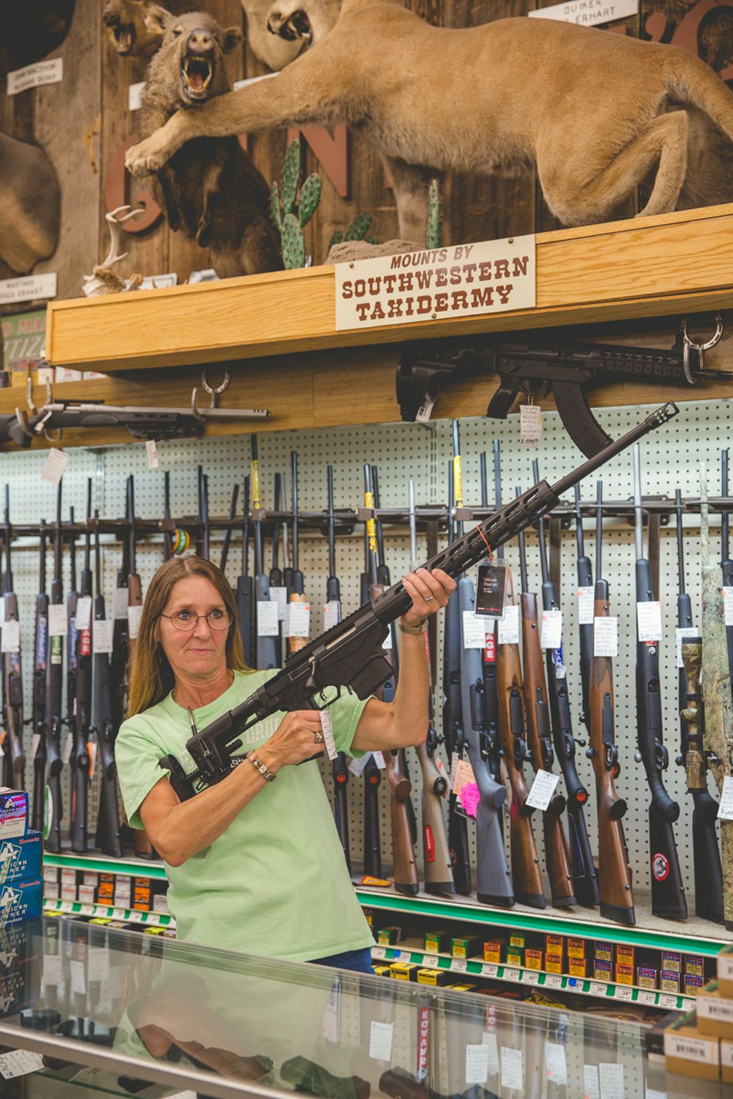 Gun shop interior displaying rifles on wall racks with taxidermy mounts above.