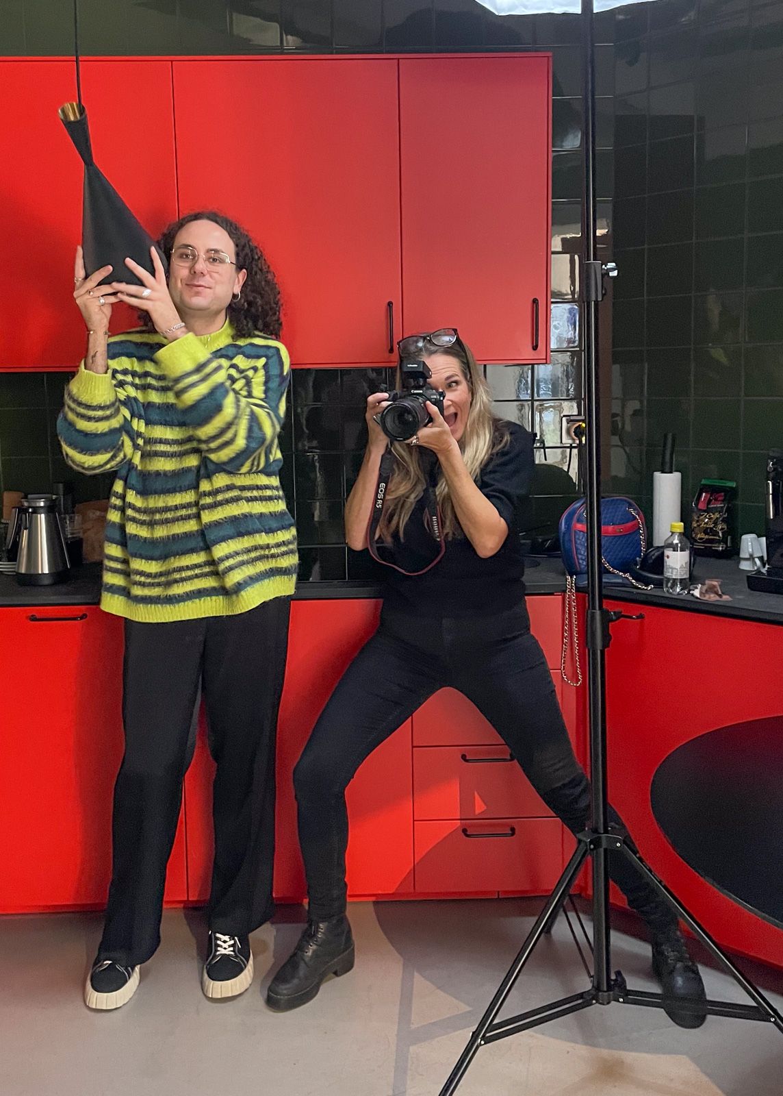 Två fotografer som arbetar tillsammans i en studio med röda väggar och fotoutrustning
