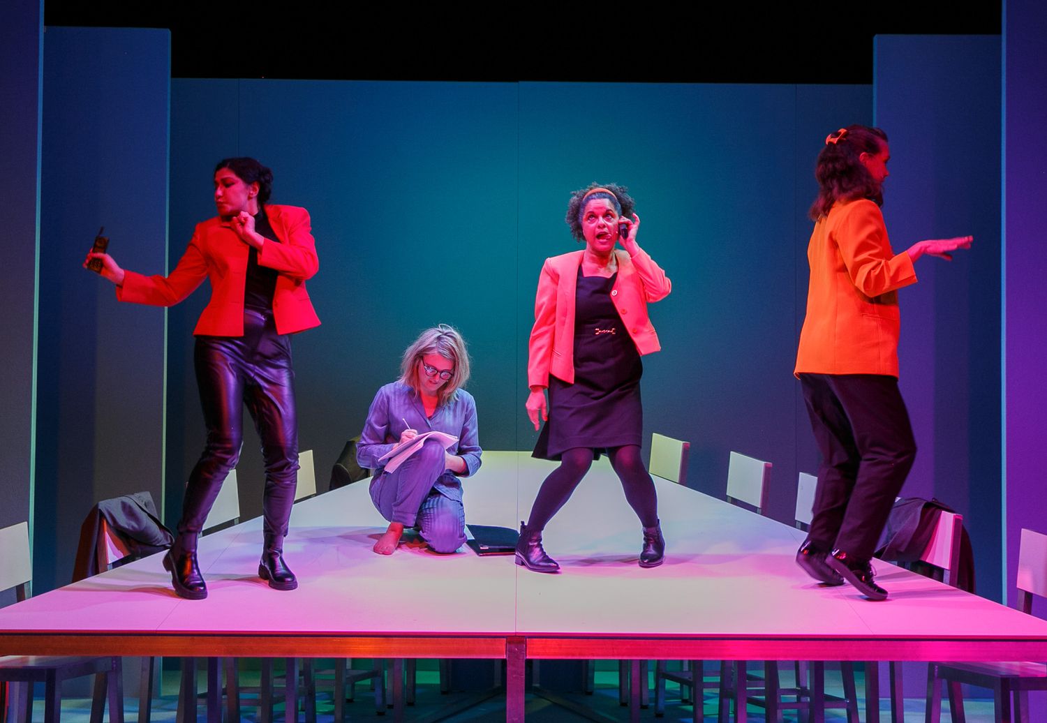 Performers move across a stage bathed in dramatic blue and pink lighting effects.