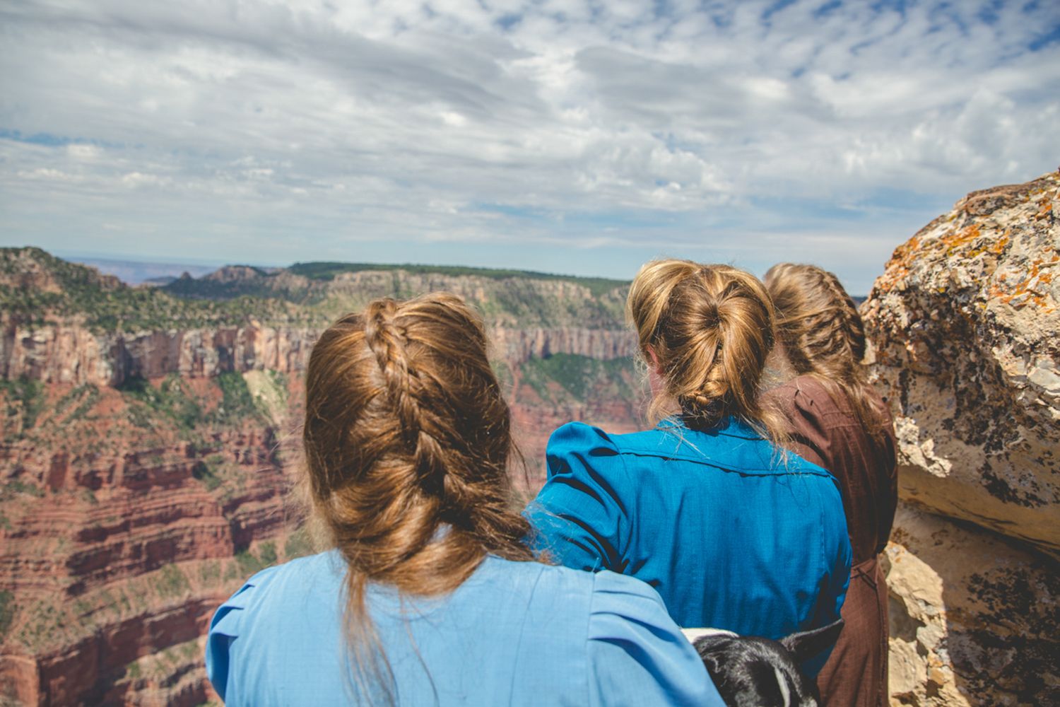 Scenic overlook of Grand Canyon with rock formations and blue sky.